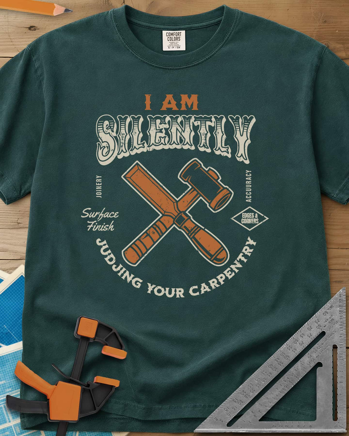 Judjing Your Carpentry heavyweight tee in Blue Spruce, a crossed chisel and mallet in a badge with small shop labels