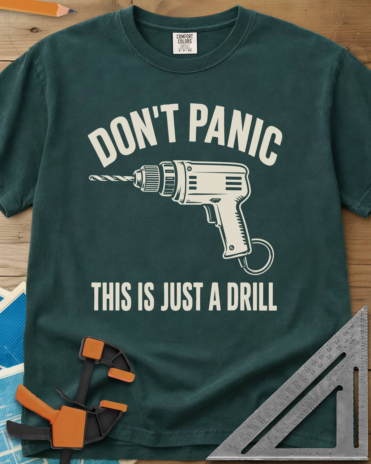 Just A Drill heavyweight tee in Blue Spruce, a corded power drill between DON’T PANIC and the punchline