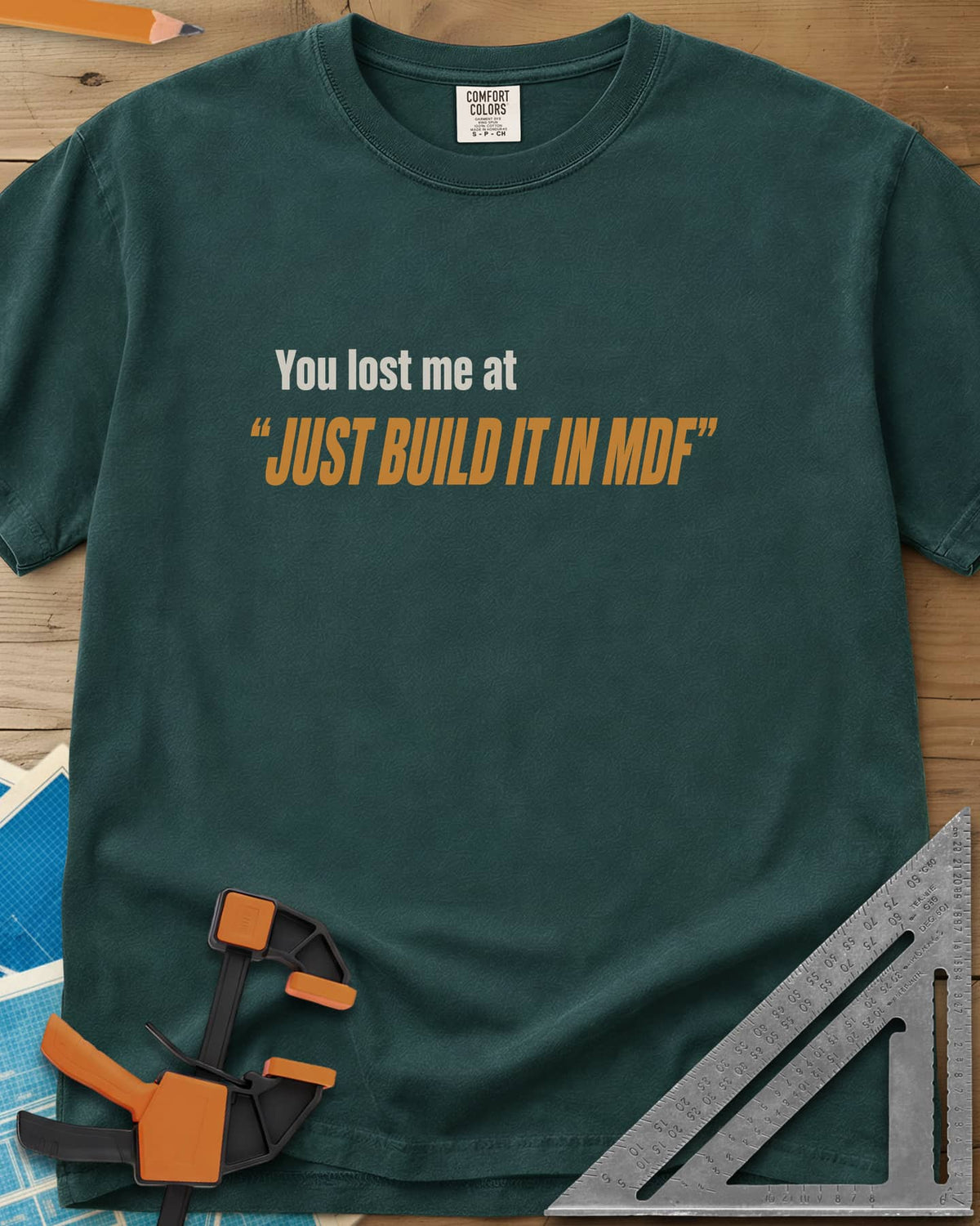 Just Build It In MDF heavyweight tee in Blue Spruce, small plain text over bold italic lettering, no graphic