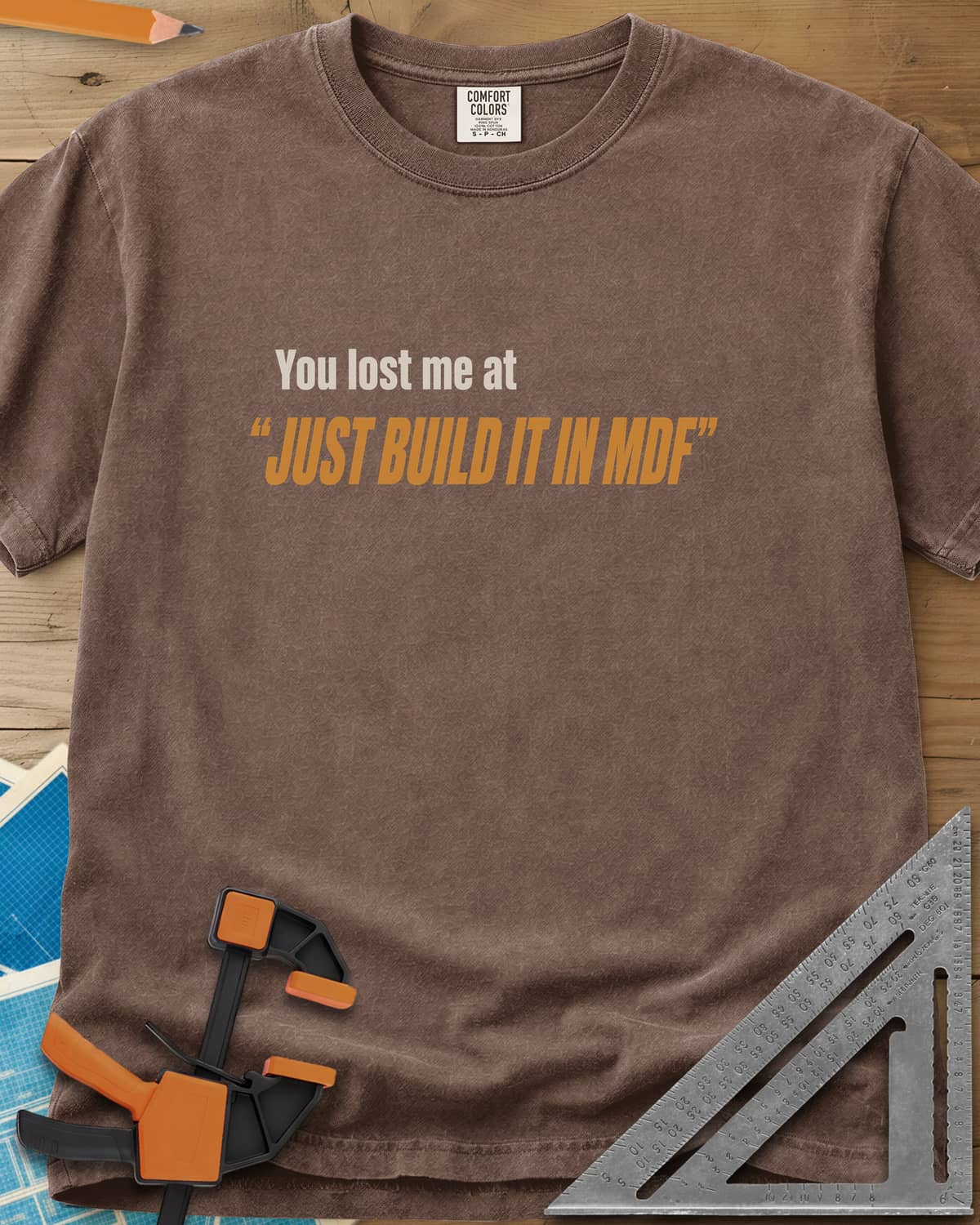 Just Build It In MDF heavyweight tee in Espresso, small plain text over bold italic lettering, no graphic