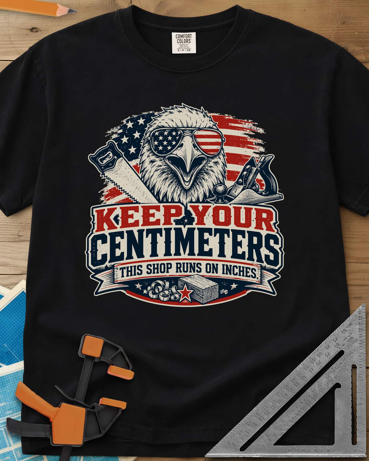 Keep Your Centimeters heavyweight tee in Black, an eagle in flag sunglasses with a handsaw, plane and banner