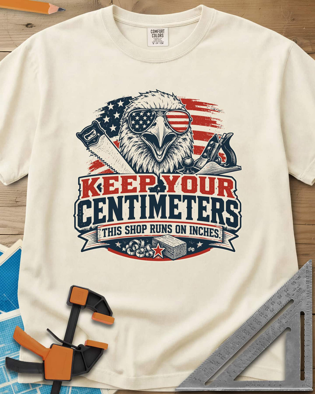 Keep Your Centimeters heavyweight tee in Ivory, an eagle in flag sunglasses with a handsaw, plane and banner