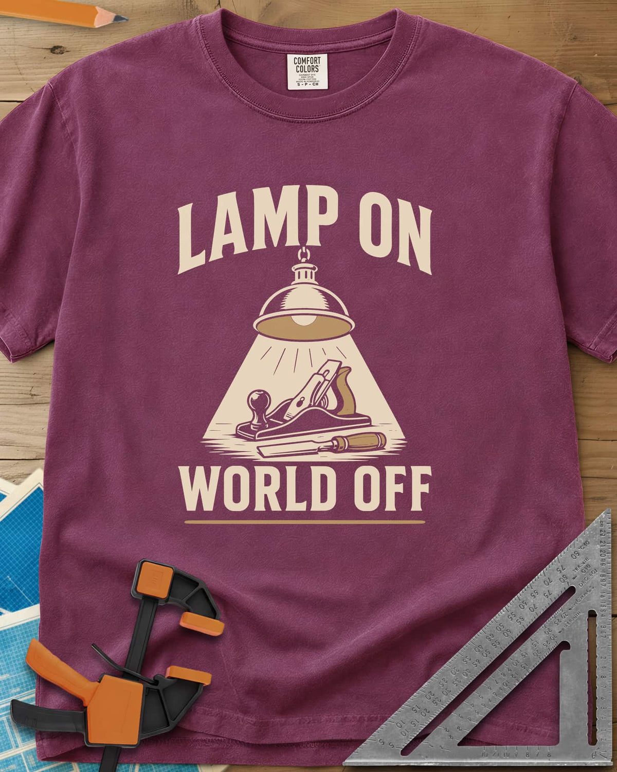 Lamp On World Off heavyweight tee in Berry, a pendant shop lamp lighting a hand plane and chisel