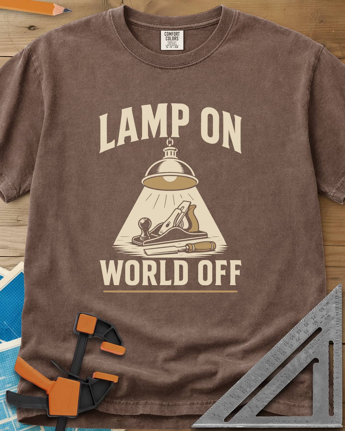 Lamp On World Off heavyweight tee in Espresso, a pendant shop lamp lighting a hand plane and chisel