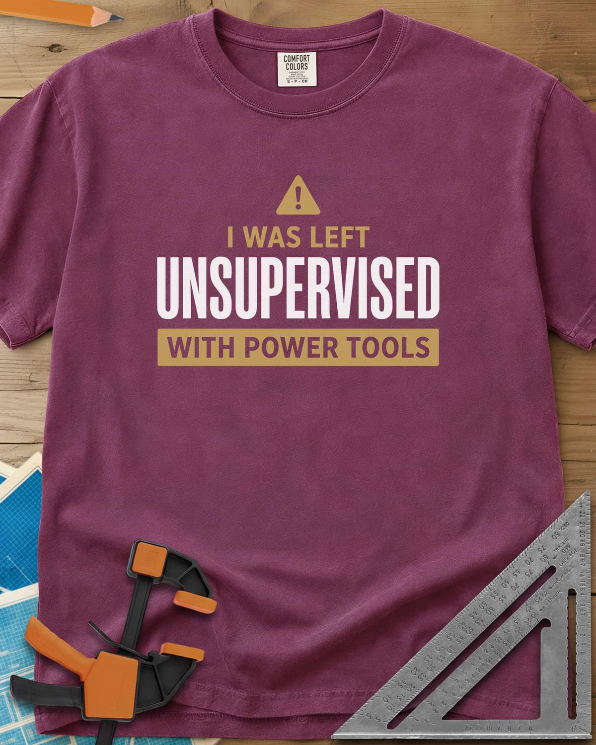 Left Unsupervised With Power Tools heavyweight tee in Berry, a warning triangle above bold lettering in a gold bar