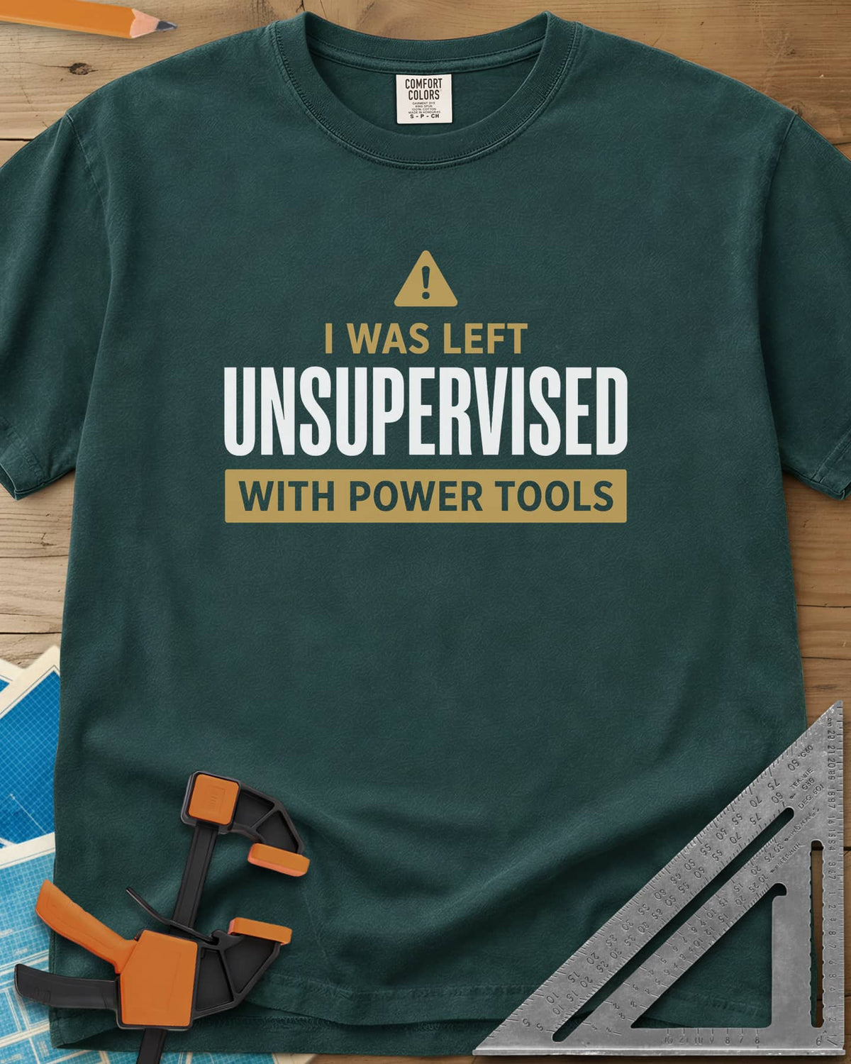Left Unsupervised With Power Tools heavyweight tee in Blue Spruce, a warning triangle above bold lettering in a gold bar
