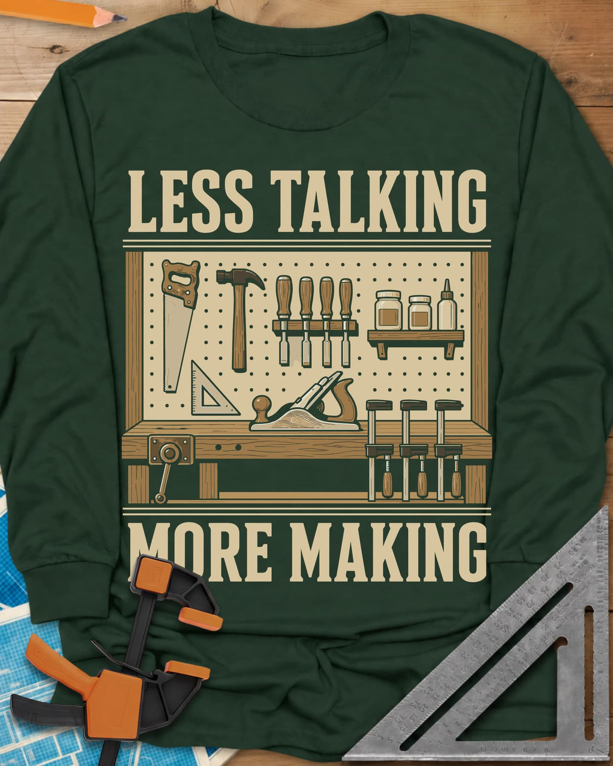 Less Talking More Making long sleeve shirt in Forest Green, a pegboard of hand tools over a workbench with a plane and clamps