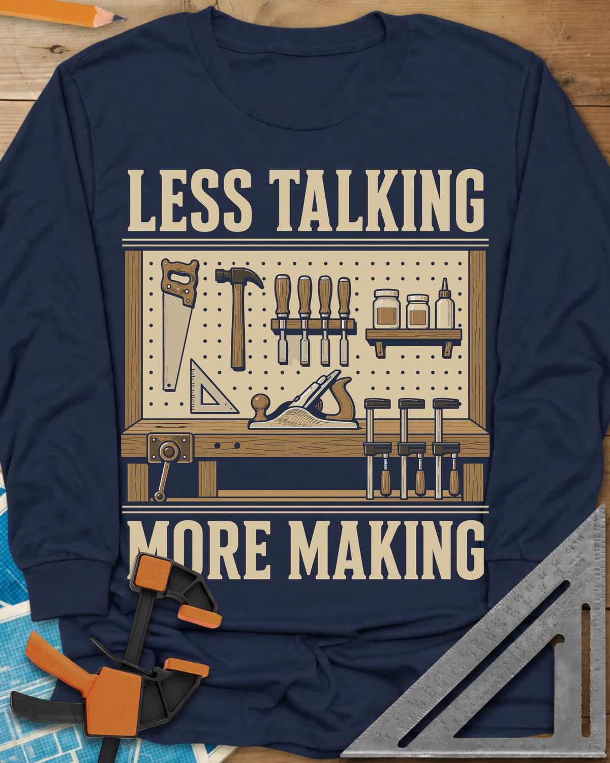 Less Talking More Making long sleeve shirt in Navy, a pegboard of hand tools over a workbench with a plane and clamps