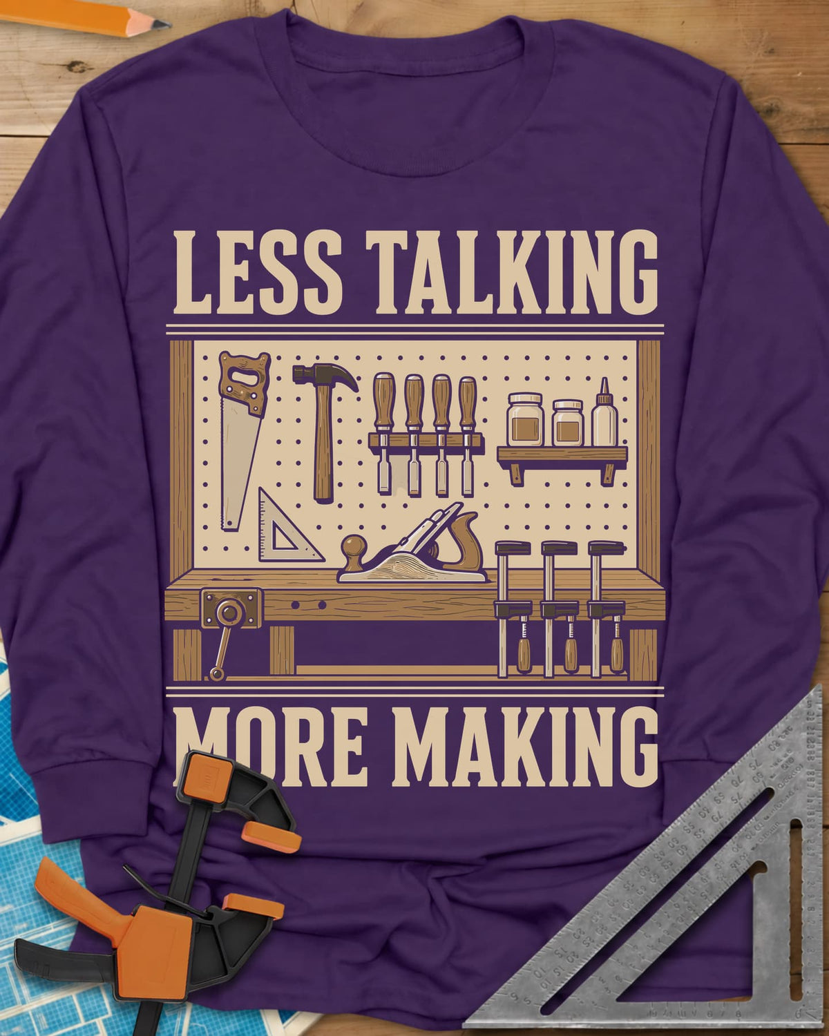Less Talking More Making long sleeve shirt in Purple, a pegboard of hand tools over a workbench with a plane and clamps