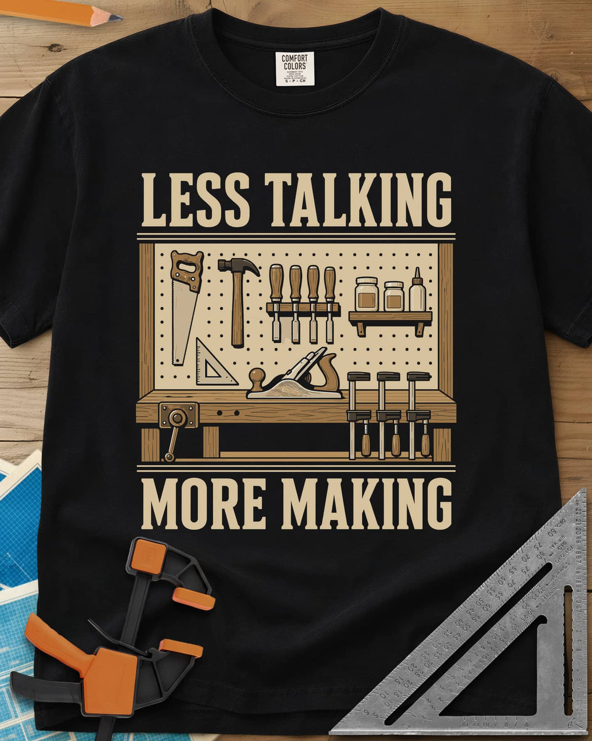 Less Talking More Making heavyweight tee in Black, a pegboard of hand tools over a workbench with a plane and clamps