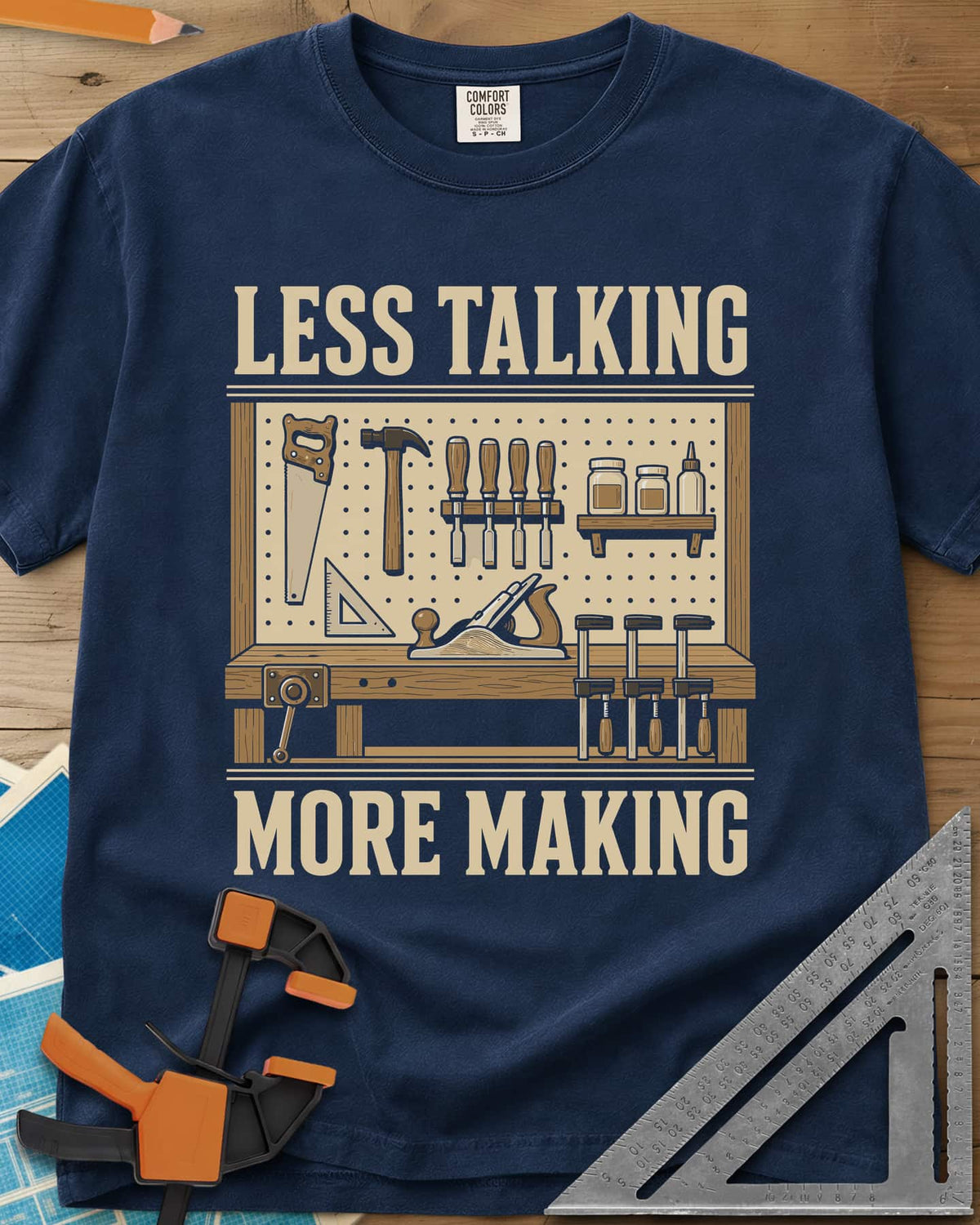 Less Talking More Making heavyweight tee in Navy, a pegboard of hand tools over a workbench with a plane and clamps