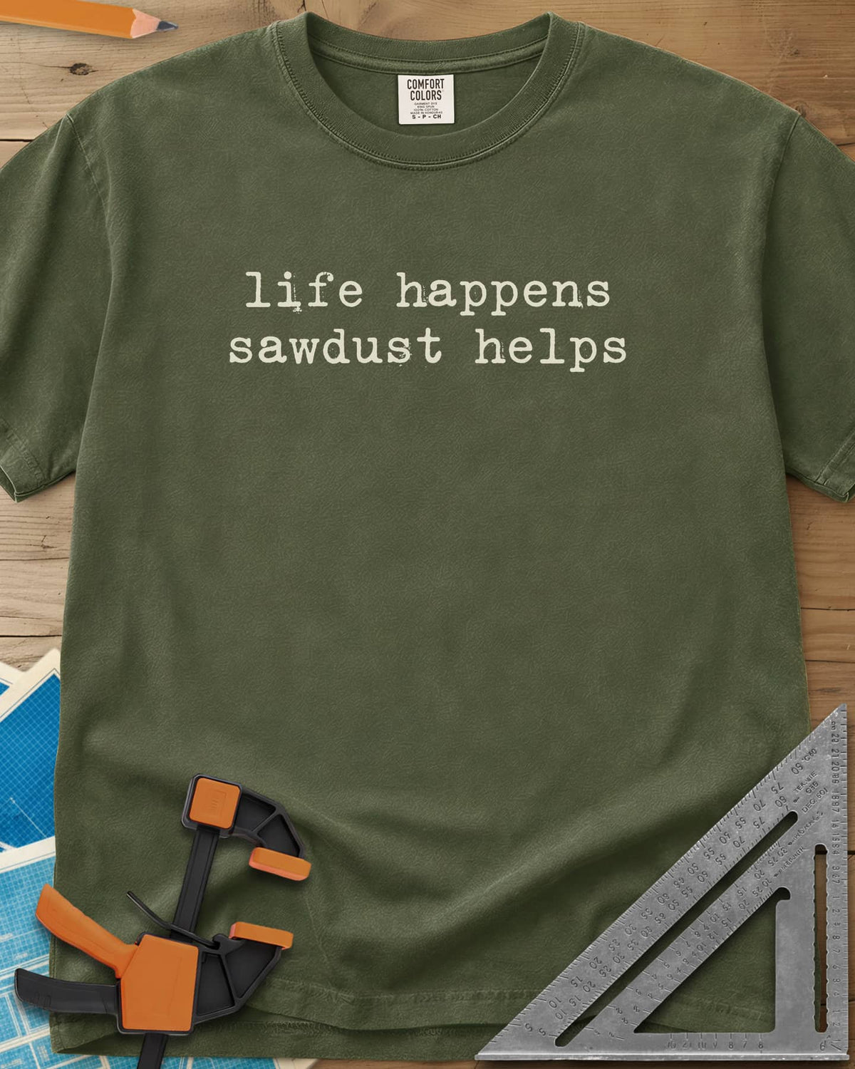 Life Happens Sawdust Helps heavyweight tee in Hemp, two lines of lowercase typewriter lettering, no graphic