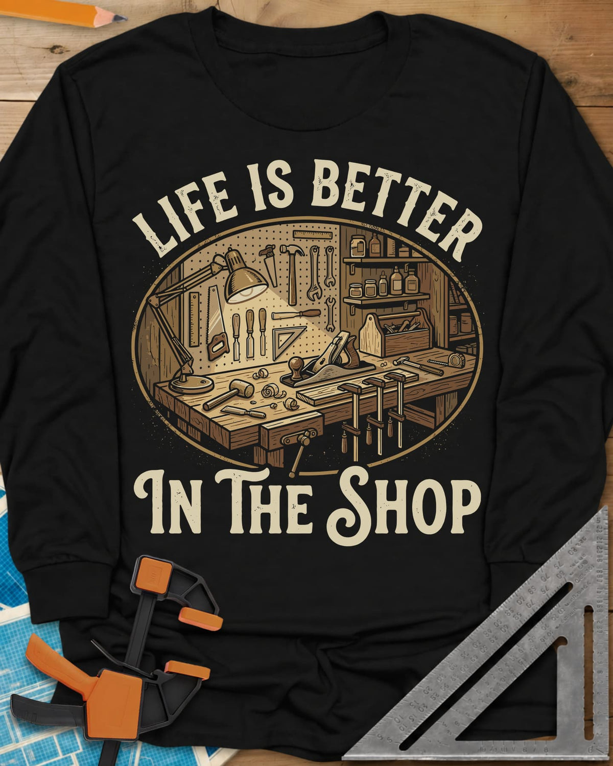 Life Is Better In The Shop long sleeve shirt in Black, a lamp-lit workbench with plane, mallet, clamps and tool pegboard