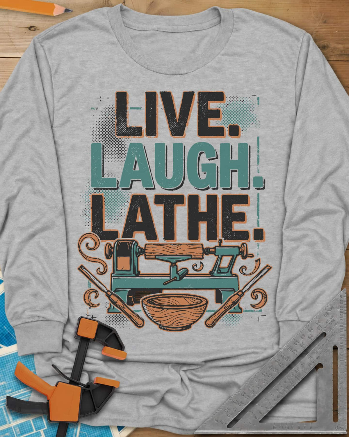 Live. Laugh. Lathe. long sleeve shirt in Sport Grey, a teal wood lathe with a bowl, two gouges and orange wood curls