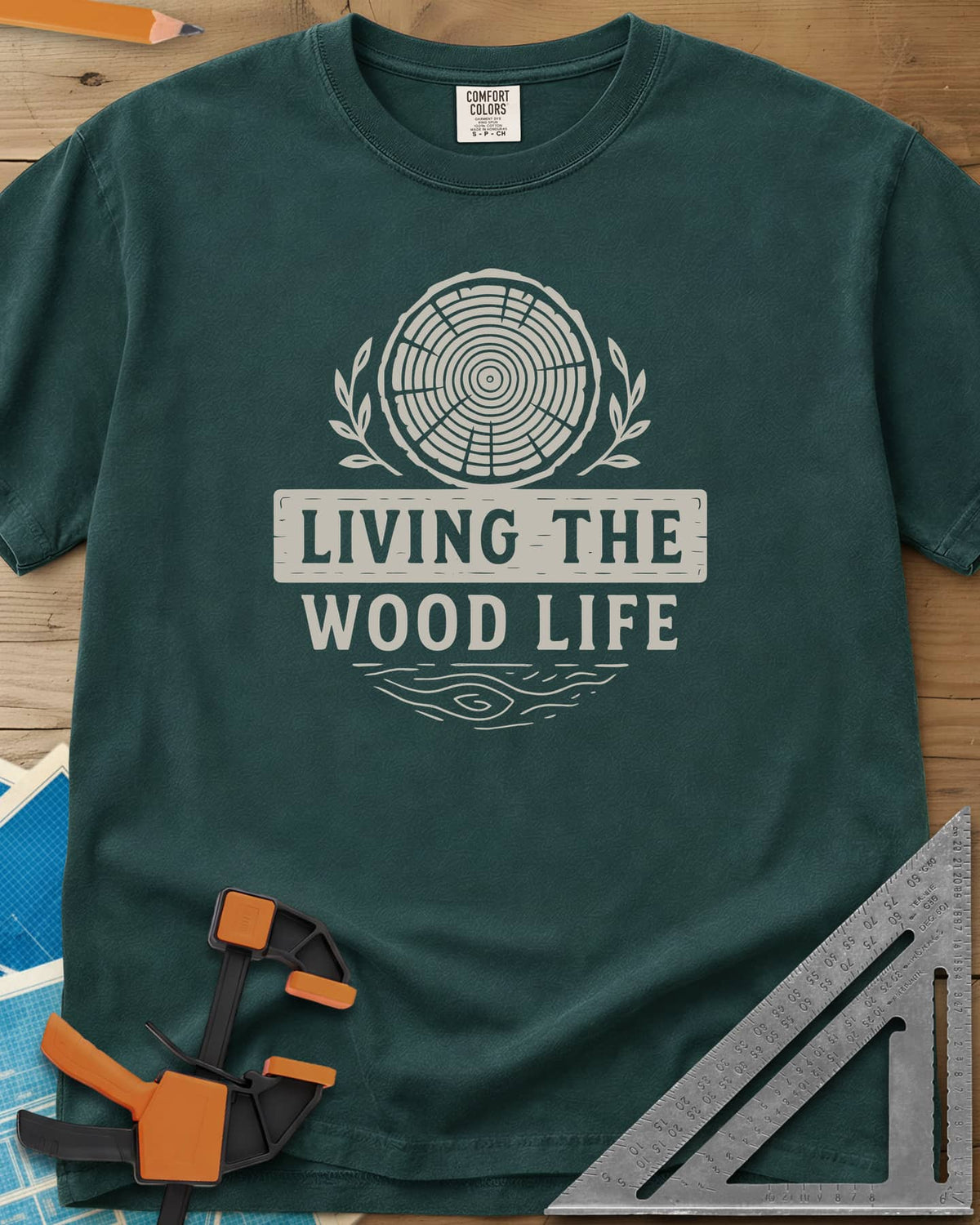 Living The Wood Life heavyweight tee in Blue Spruce, a log slice with laurel sprigs and a plank banner