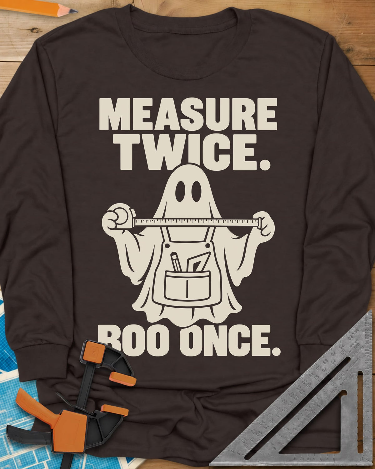 Measure Twice, Boo Once long sleeve shirt in Dark Chocolate, a ghost in a tool apron holding a stretched tape measure