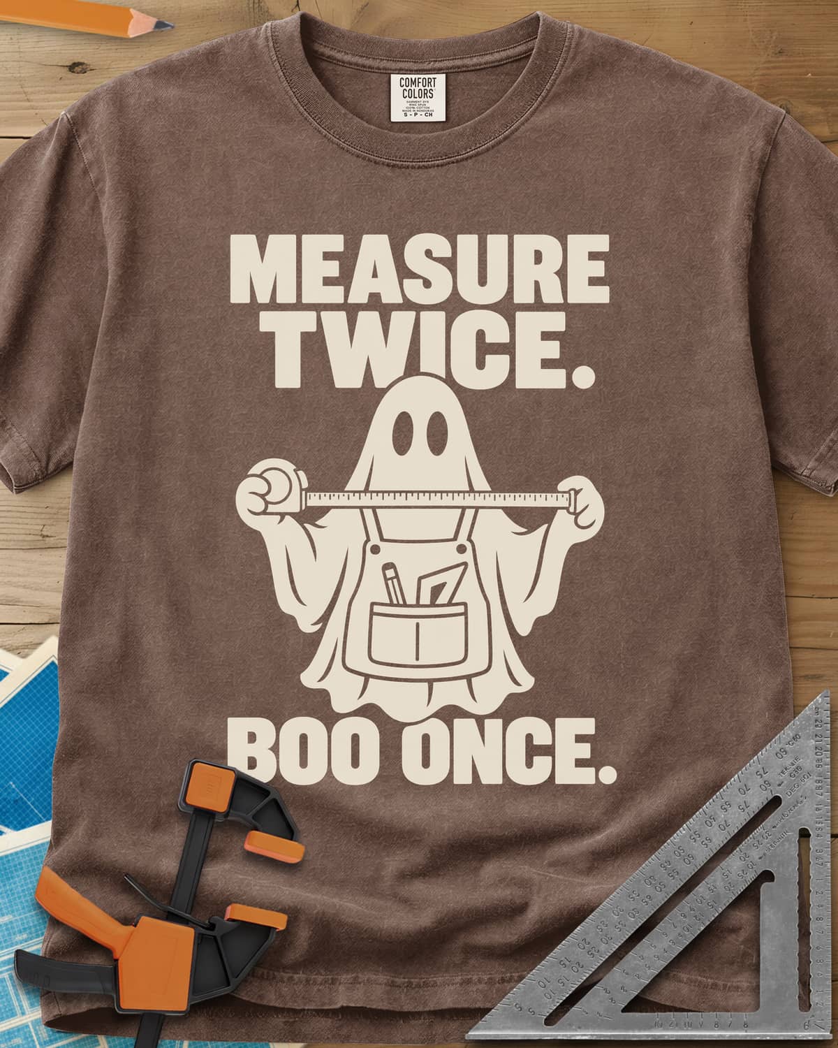 Measure Twice, Boo Once heavyweight tee in Espresso, a ghost in a tool apron holding a stretched tape measure