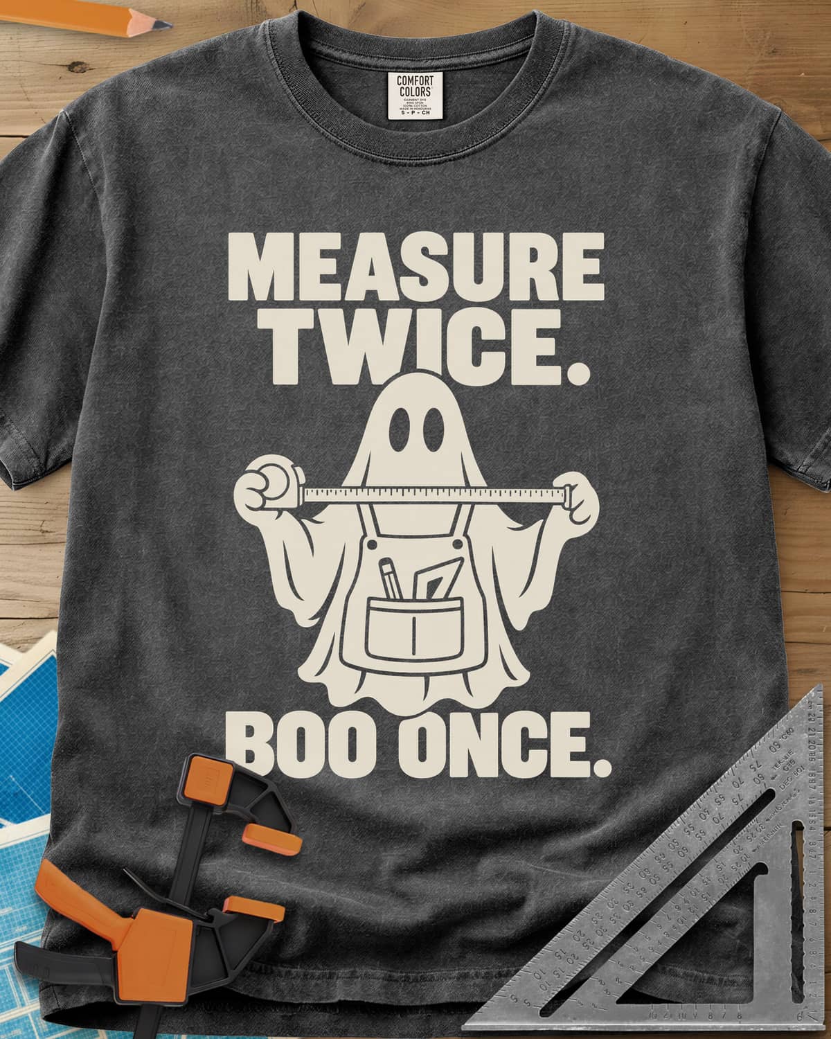Measure Twice, Boo Once heavyweight tee in Pepper, a ghost in a tool apron holding a stretched tape measure