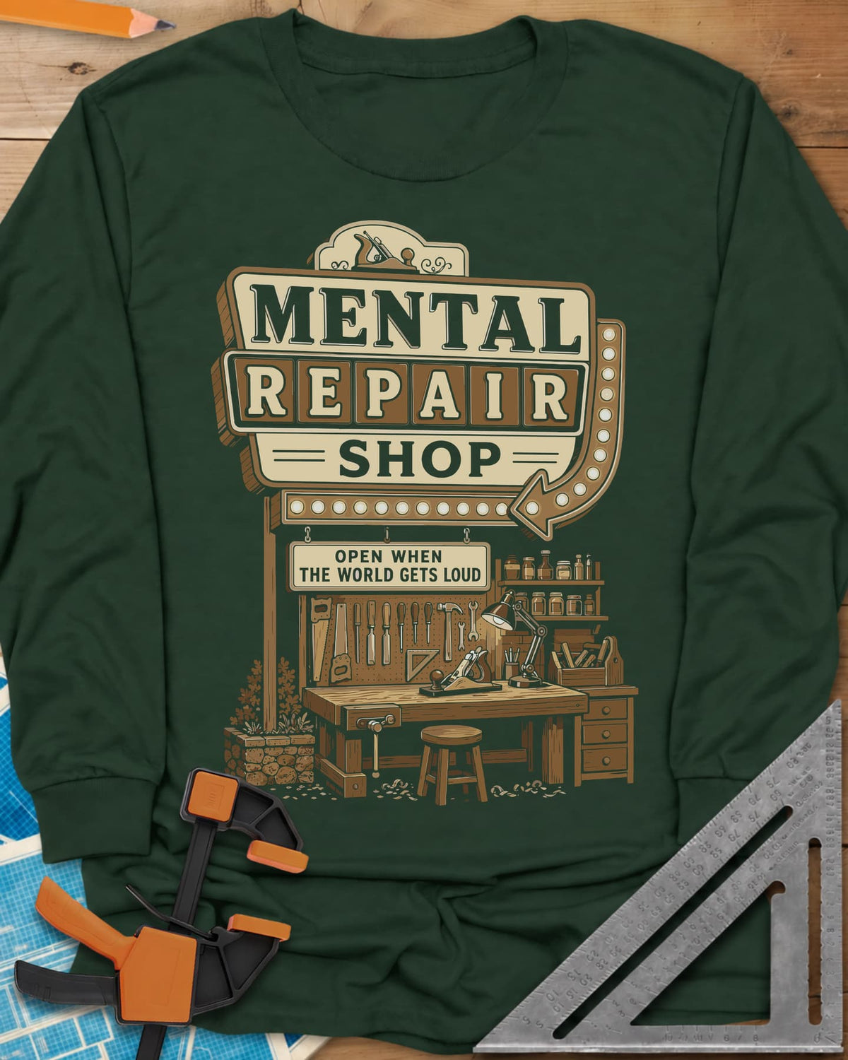 Mental Repair Shop long sleeve shirt in Forest Green, a retro roadside sign over a tidy woodworking bench and pegboard