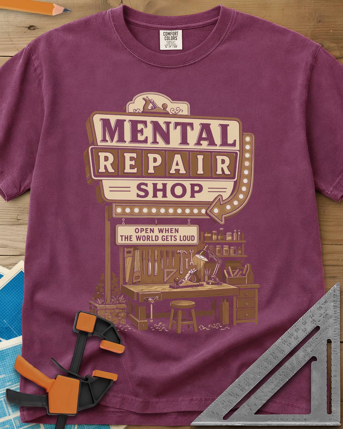 Mental Repair Shop heavyweight tee in Berry, a retro roadside sign over a tidy woodworking bench and pegboard