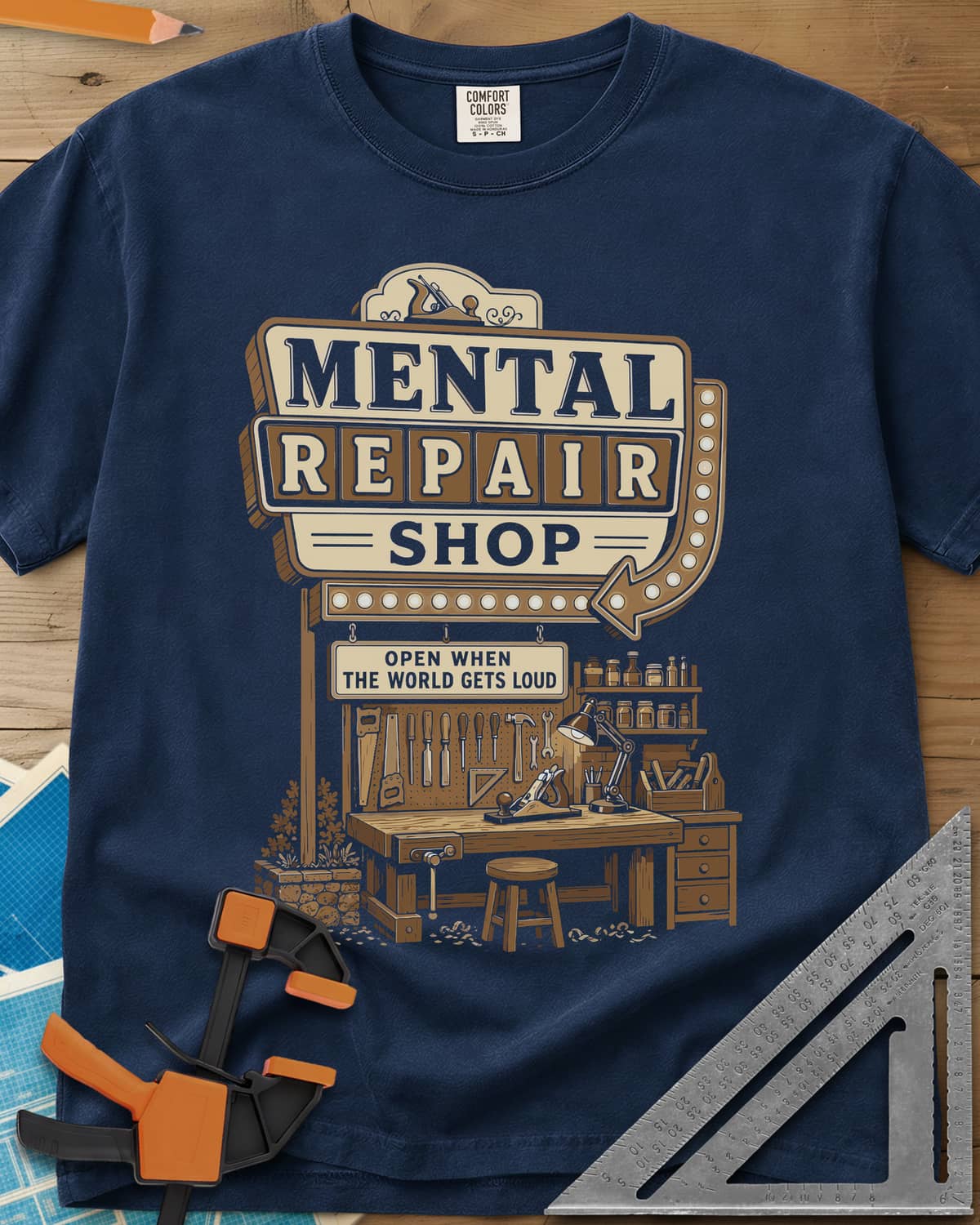 Mental Repair Shop heavyweight tee in Navy, a retro roadside sign over a tidy woodworking bench and pegboard