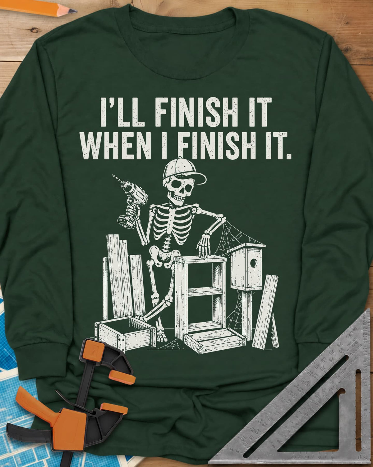 Misses Me At Work long sleeve shirt in Forest Green, a skeleton in a ball cap with a drill among half-built projects