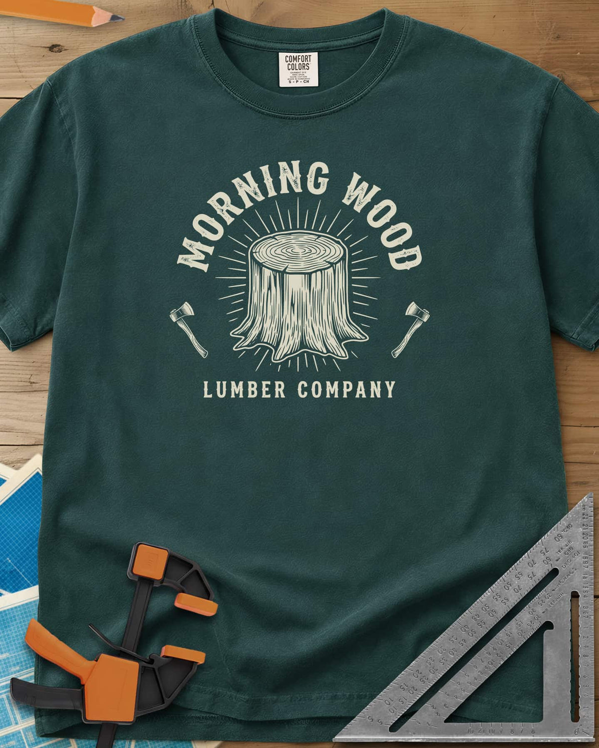 Morning Wood Lumber Company heavyweight tee in Blue Spruce, a tree stump with sunburst rays between two axes