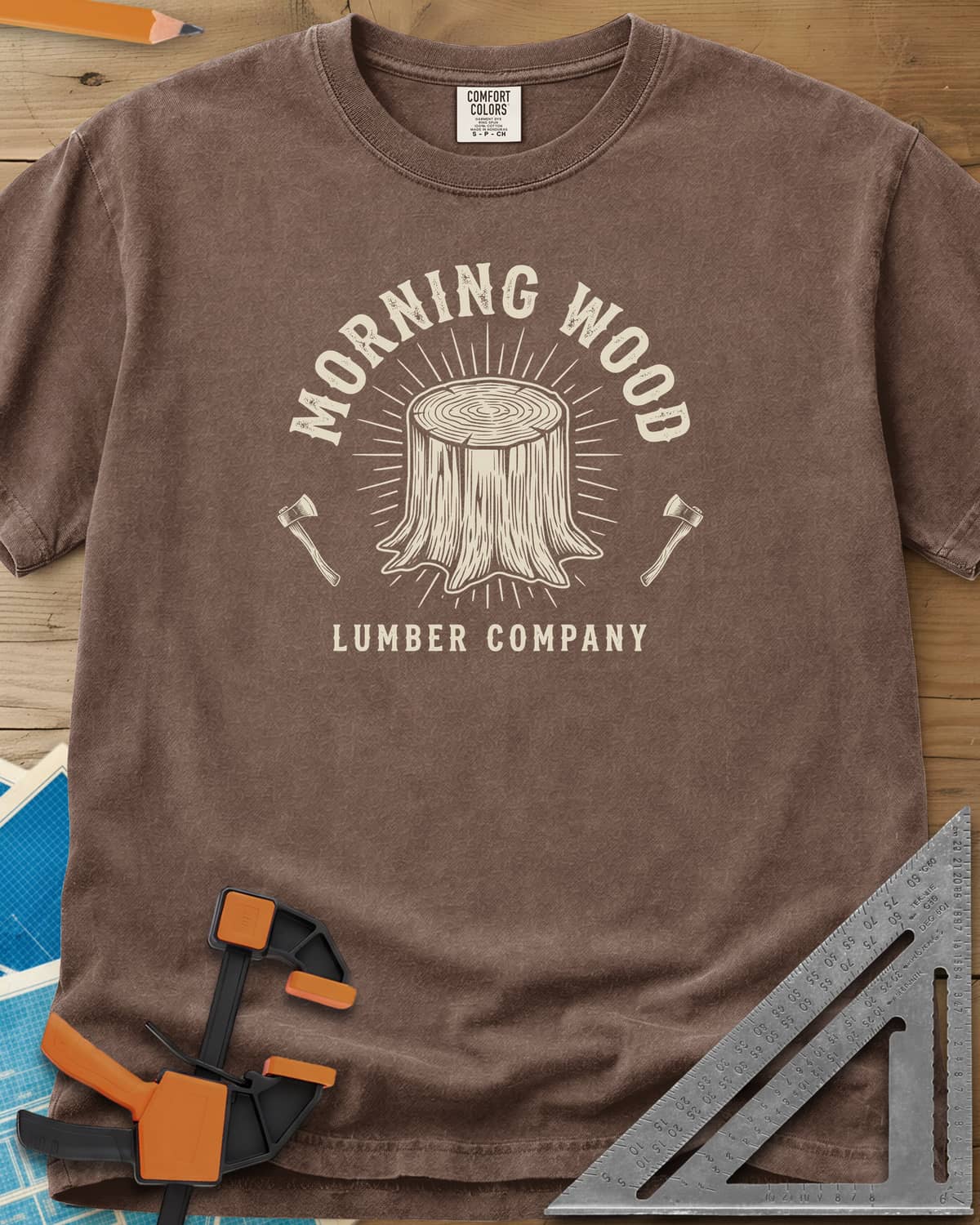 Morning Wood Lumber Company heavyweight tee in Espresso, a tree stump with sunburst rays between two axes