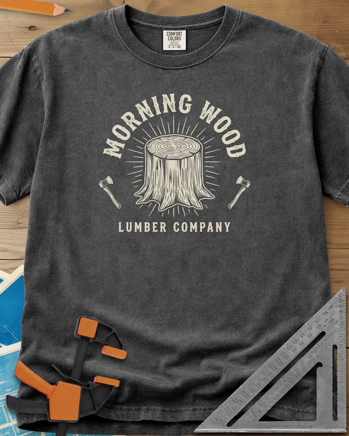 Morning Wood Lumber Company heavyweight tee in Pepper, a tree stump with sunburst rays between two axes