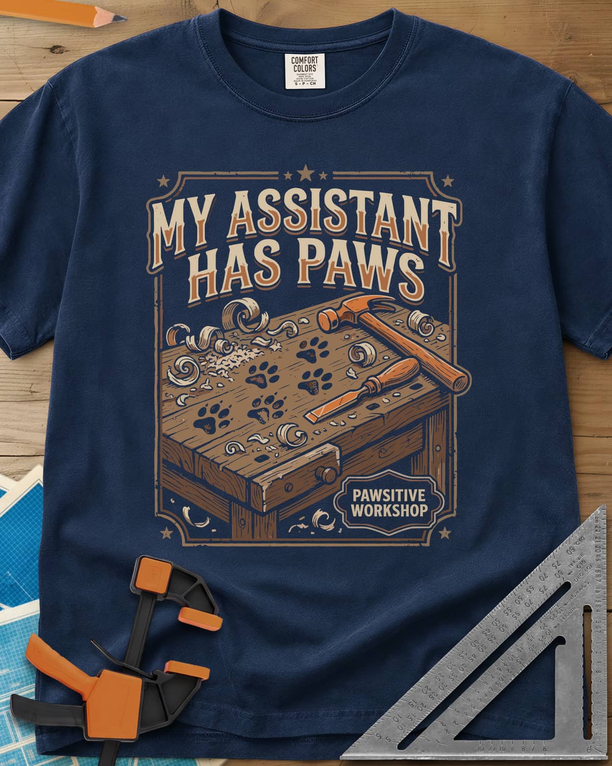 My Assistant Has Paws heavyweight tee in Navy, workbench with paw prints, shavings, a hammer and a chisel
