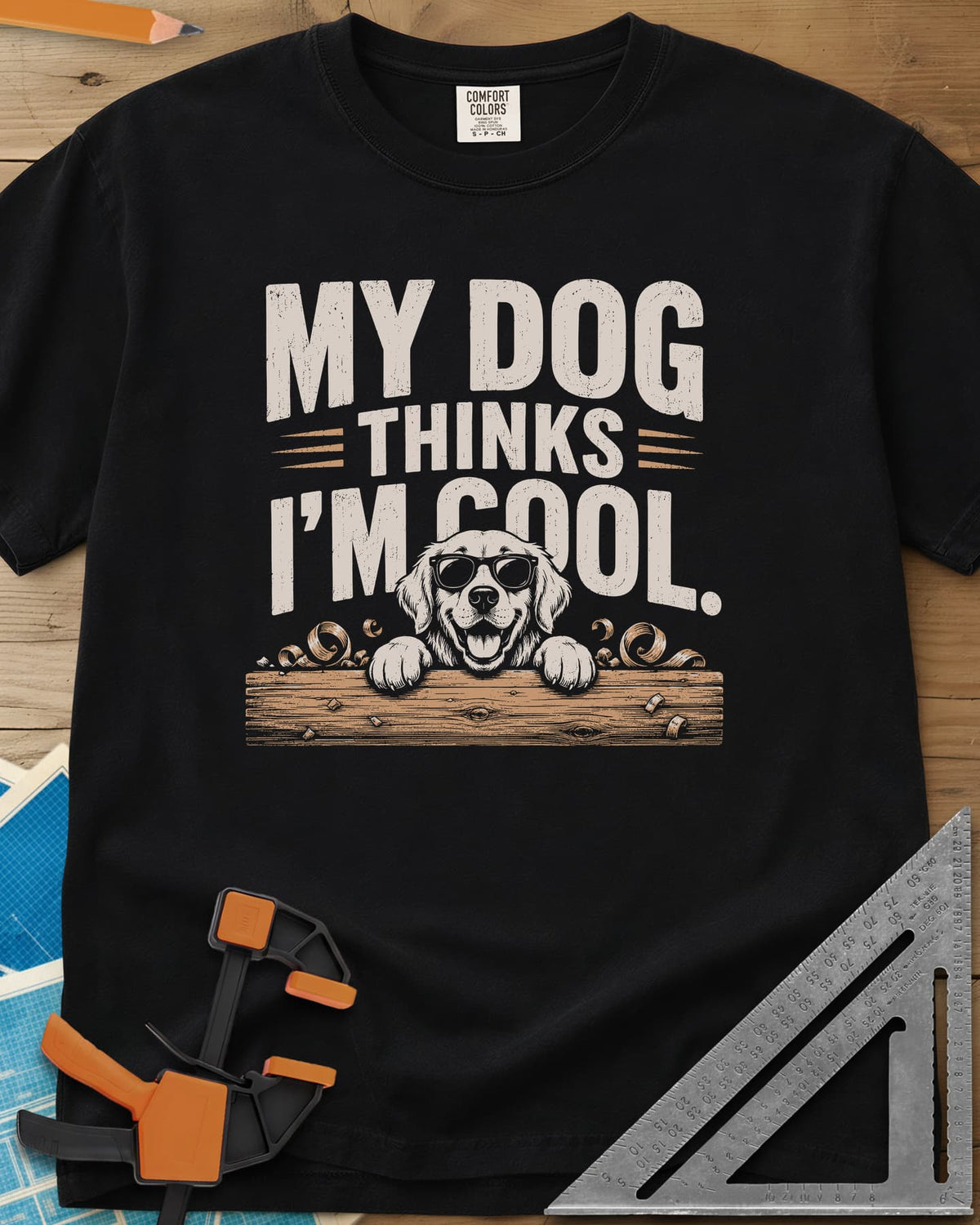 My Dog Thinks I’m Cool heavyweight tee in Black, a golden retriever in sunglasses peeking over a wood plank