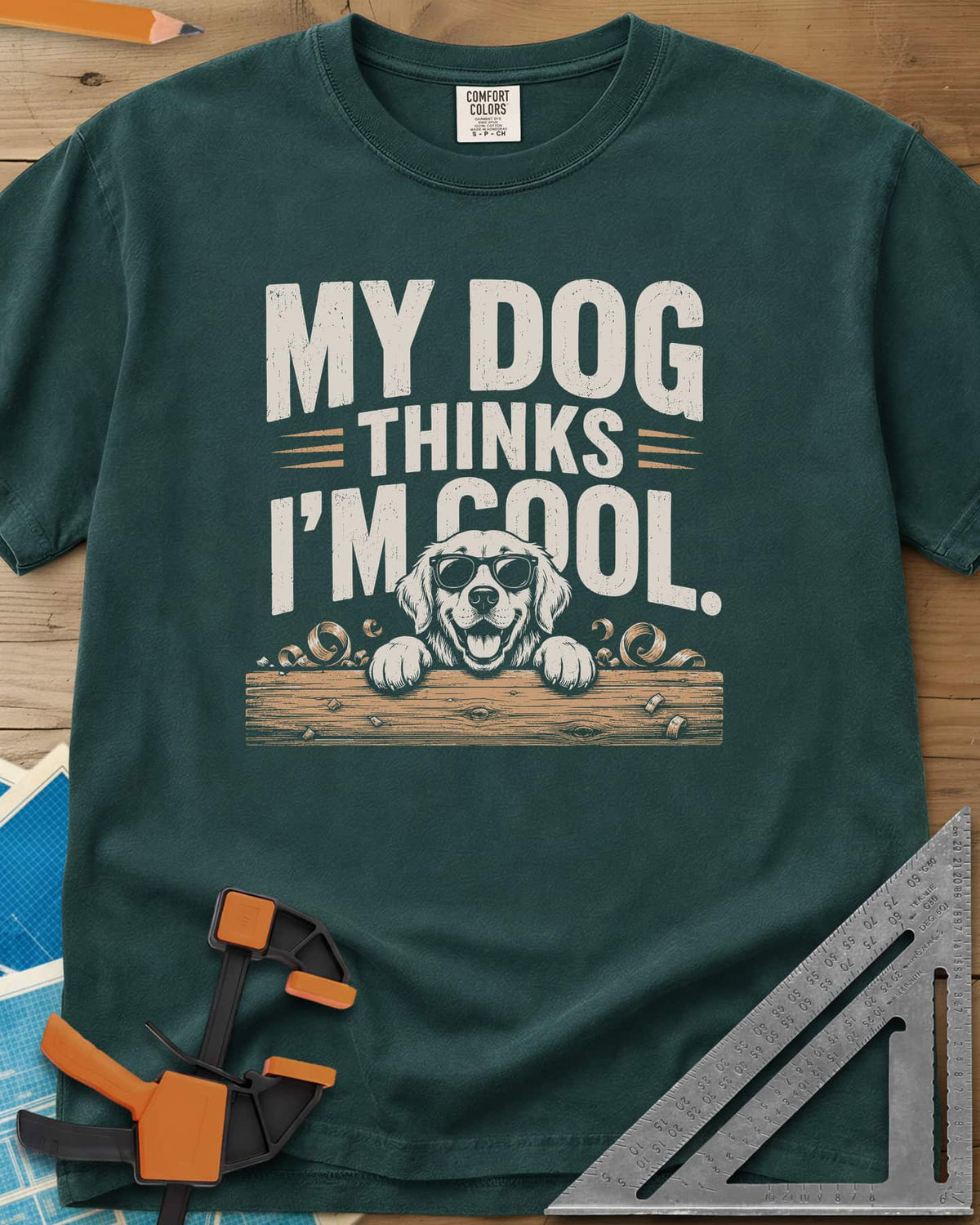 My Dog Thinks I’m Cool heavyweight tee in Blue Spruce, a golden retriever in sunglasses peeking over a wood plank