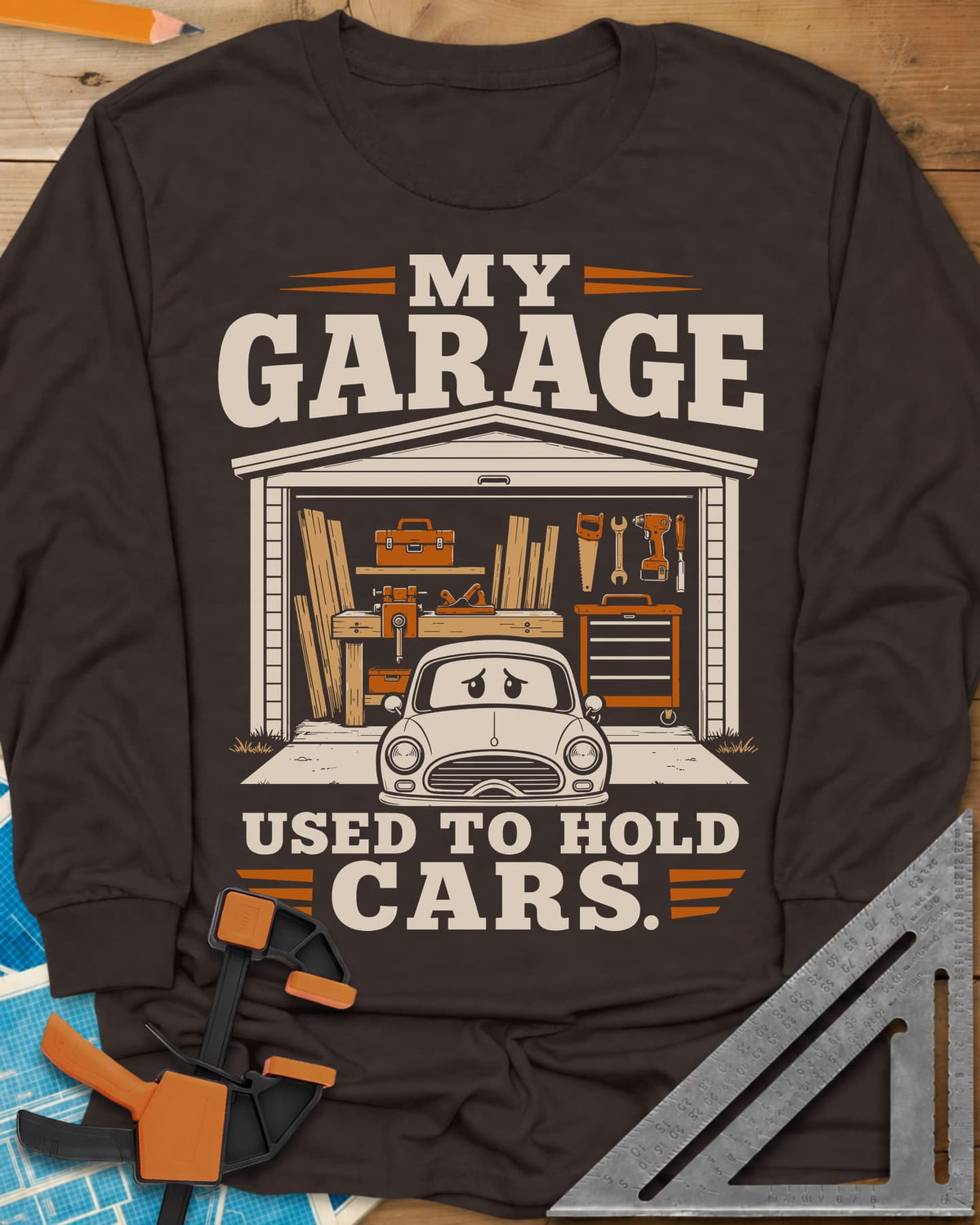 My Garage Used To Hold Cars long sleeve shirt in Dark Chocolate, an open garage full of lumber and tools with a worried car