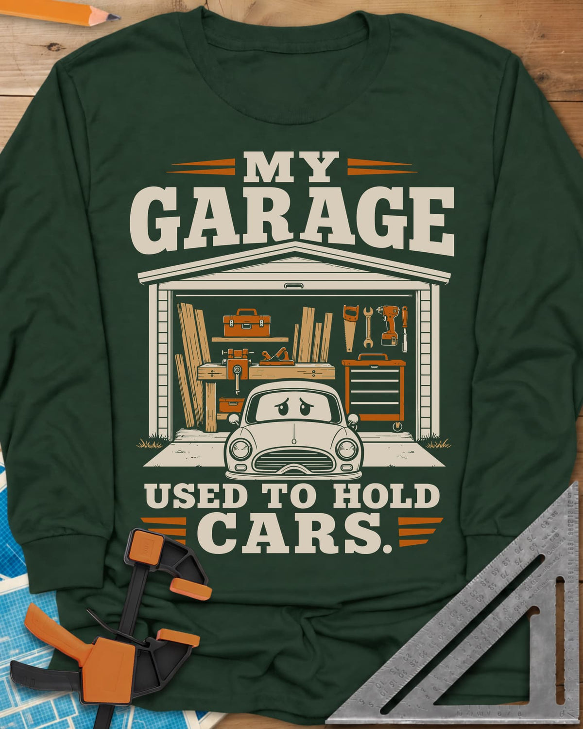 My Garage Used To Hold Cars long sleeve shirt in Forest Green, an open garage full of lumber and tools with a worried car