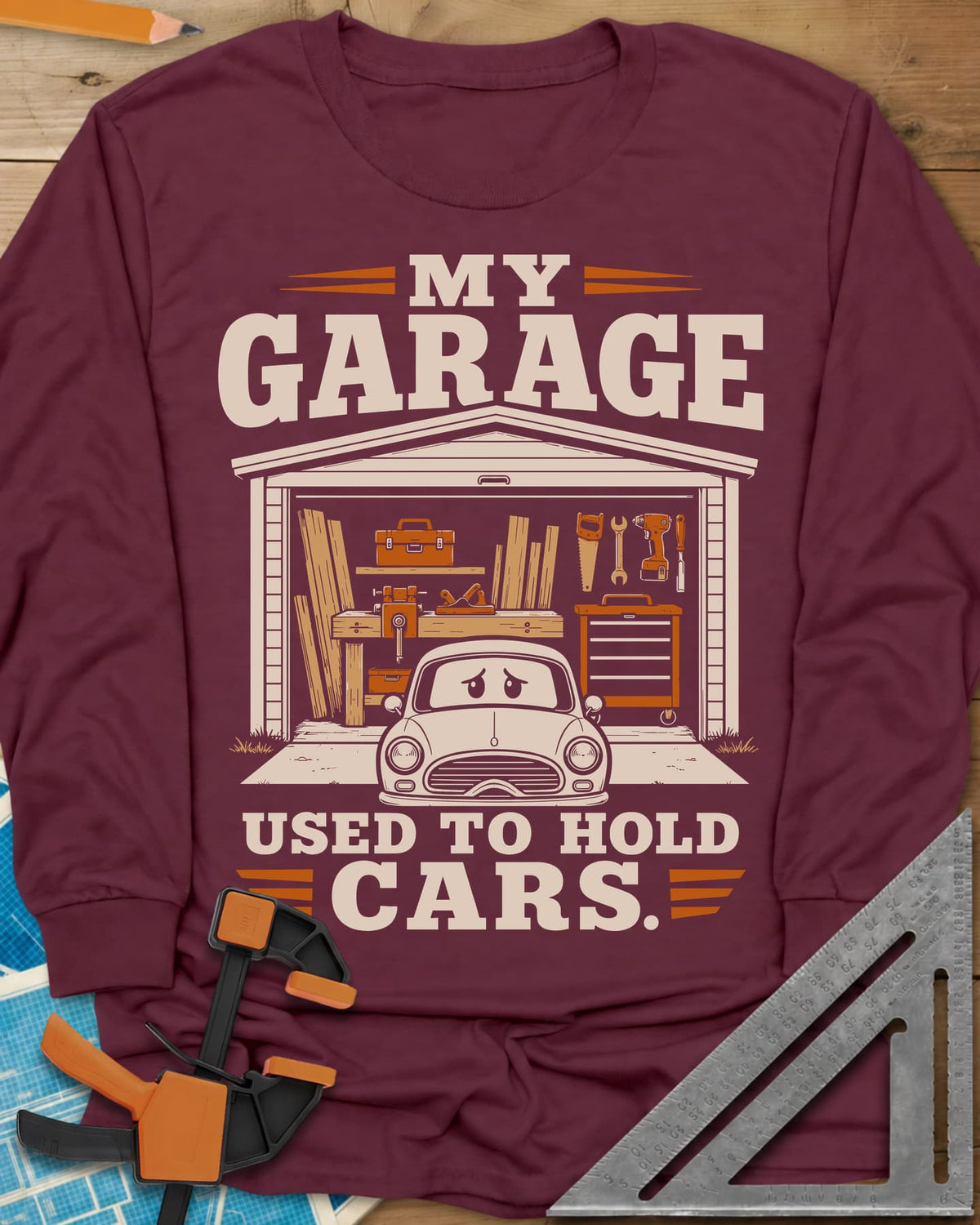My Garage Used To Hold Cars long sleeve shirt in Maroon, an open garage full of lumber and tools with a worried car