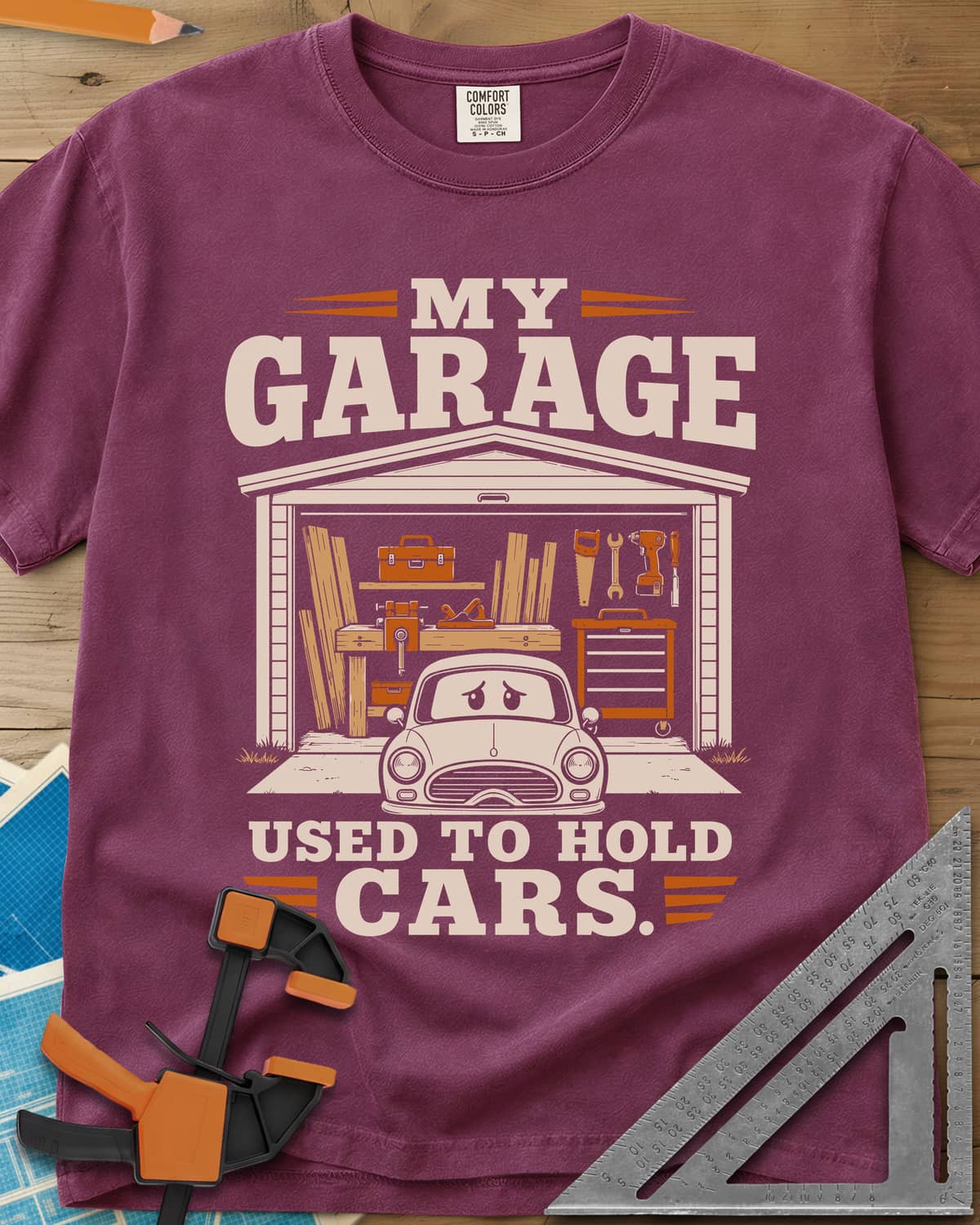 My Garage Used To Hold Cars heavyweight tee in Berry, an open garage full of lumber and tools with a worried car