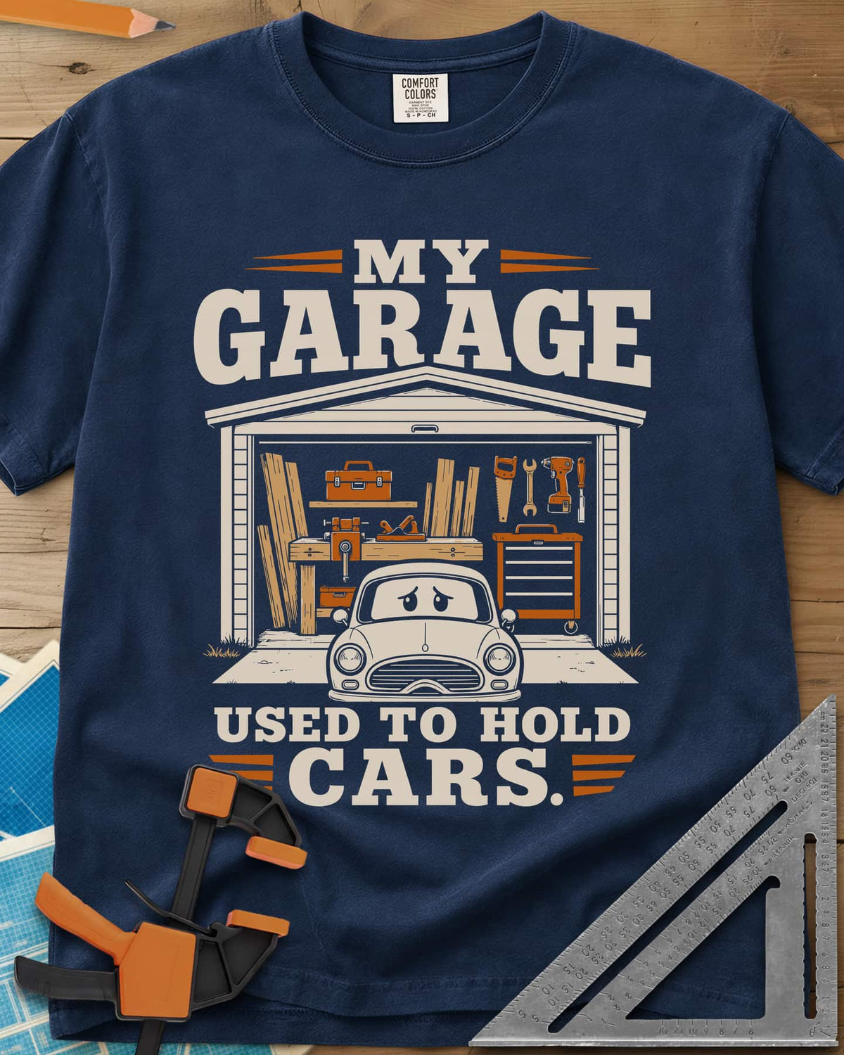 My Garage Used To Hold Cars heavyweight tee in Navy, an open garage full of lumber and tools with a worried car