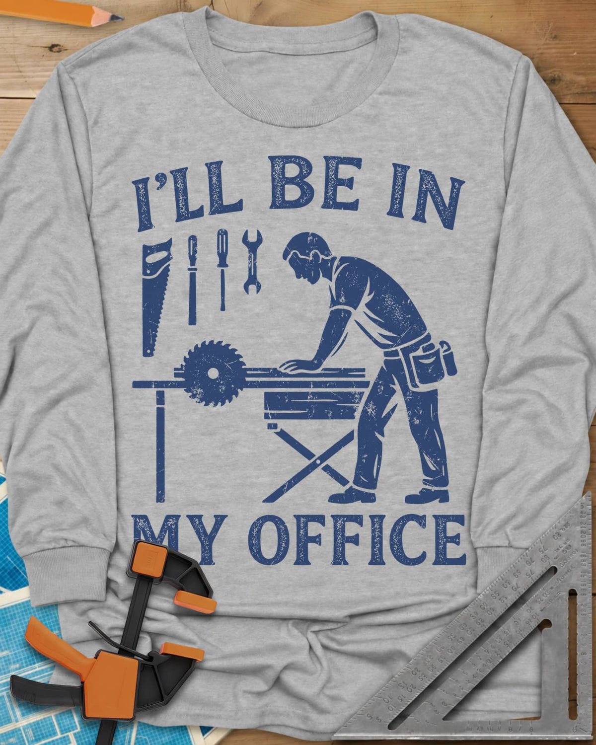 My Office long sleeve shirt in Sport Grey, a woodworker at a table saw with hand tools hung above
