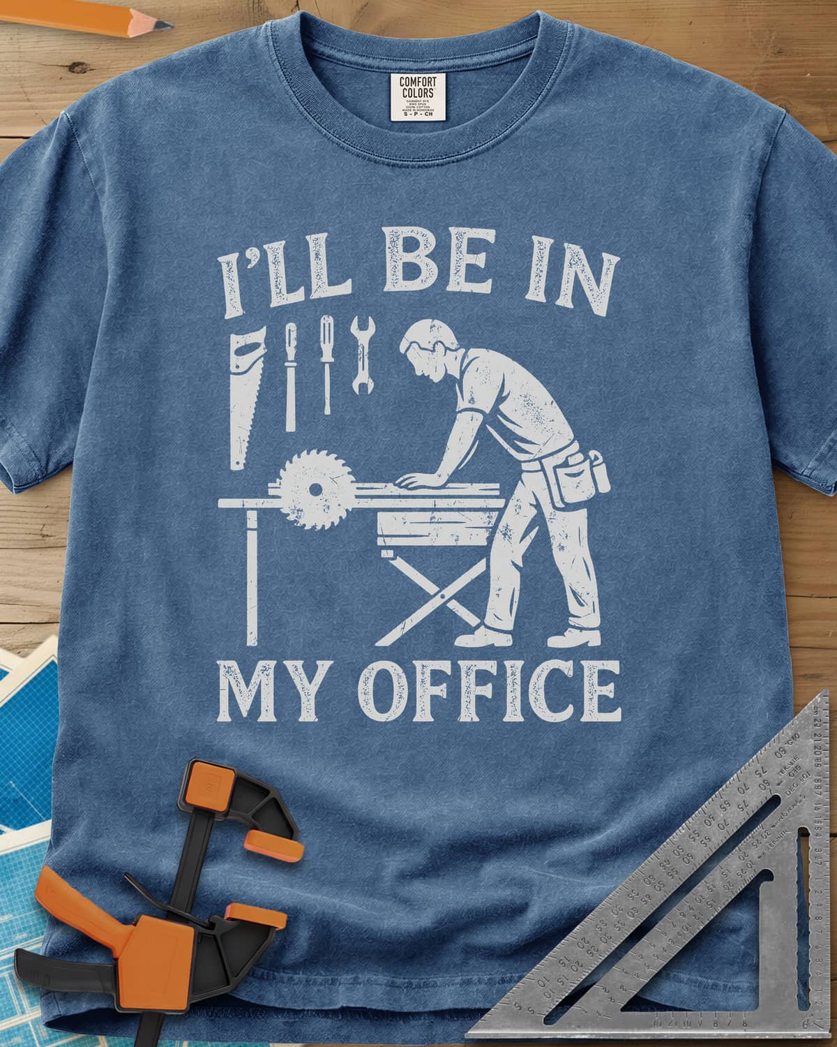 My Office heavyweight tee in Blue Jean, a woodworker at a table saw with hand tools hung above