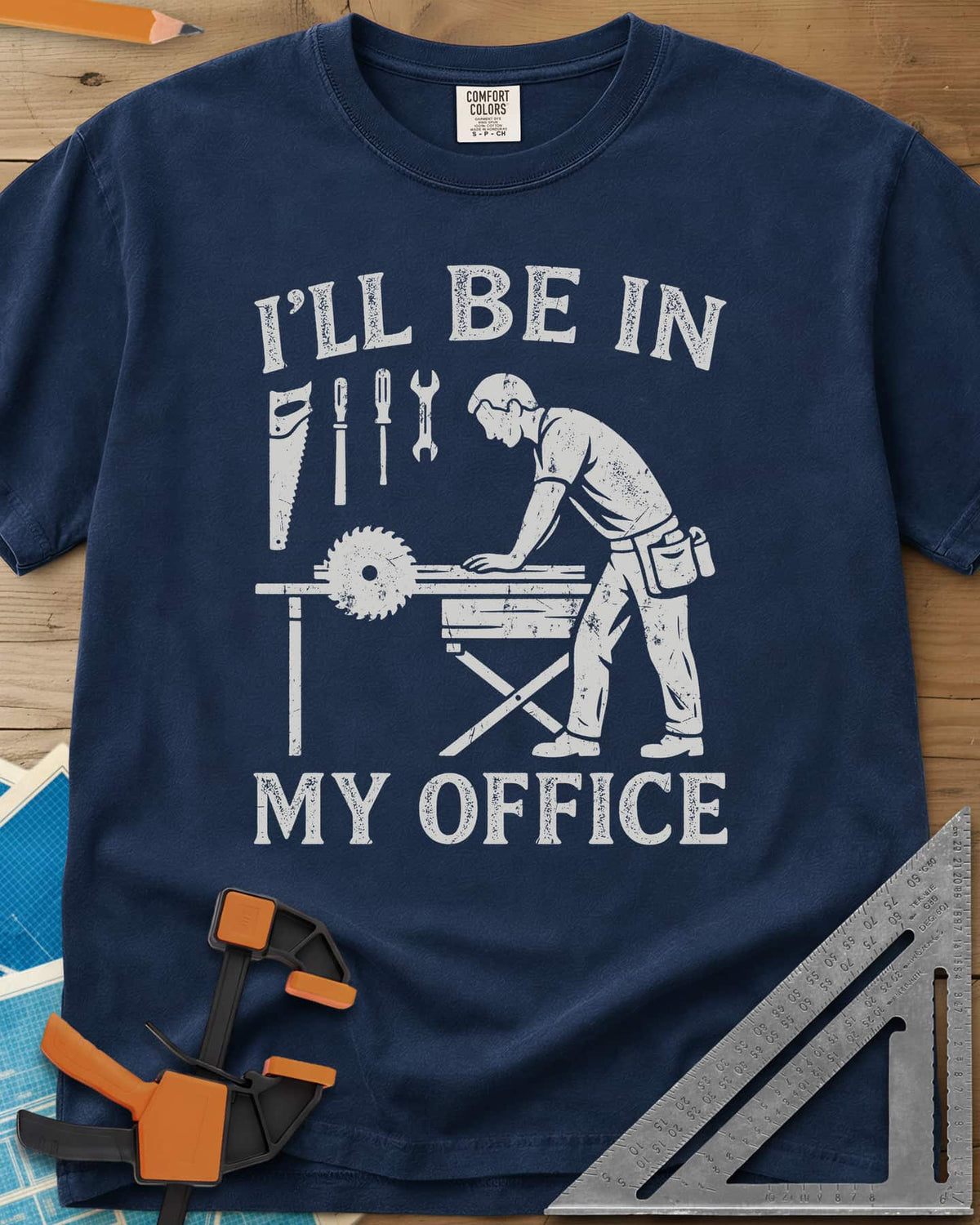 My Office heavyweight tee in Navy, a woodworker at a table saw with hand tools hung above