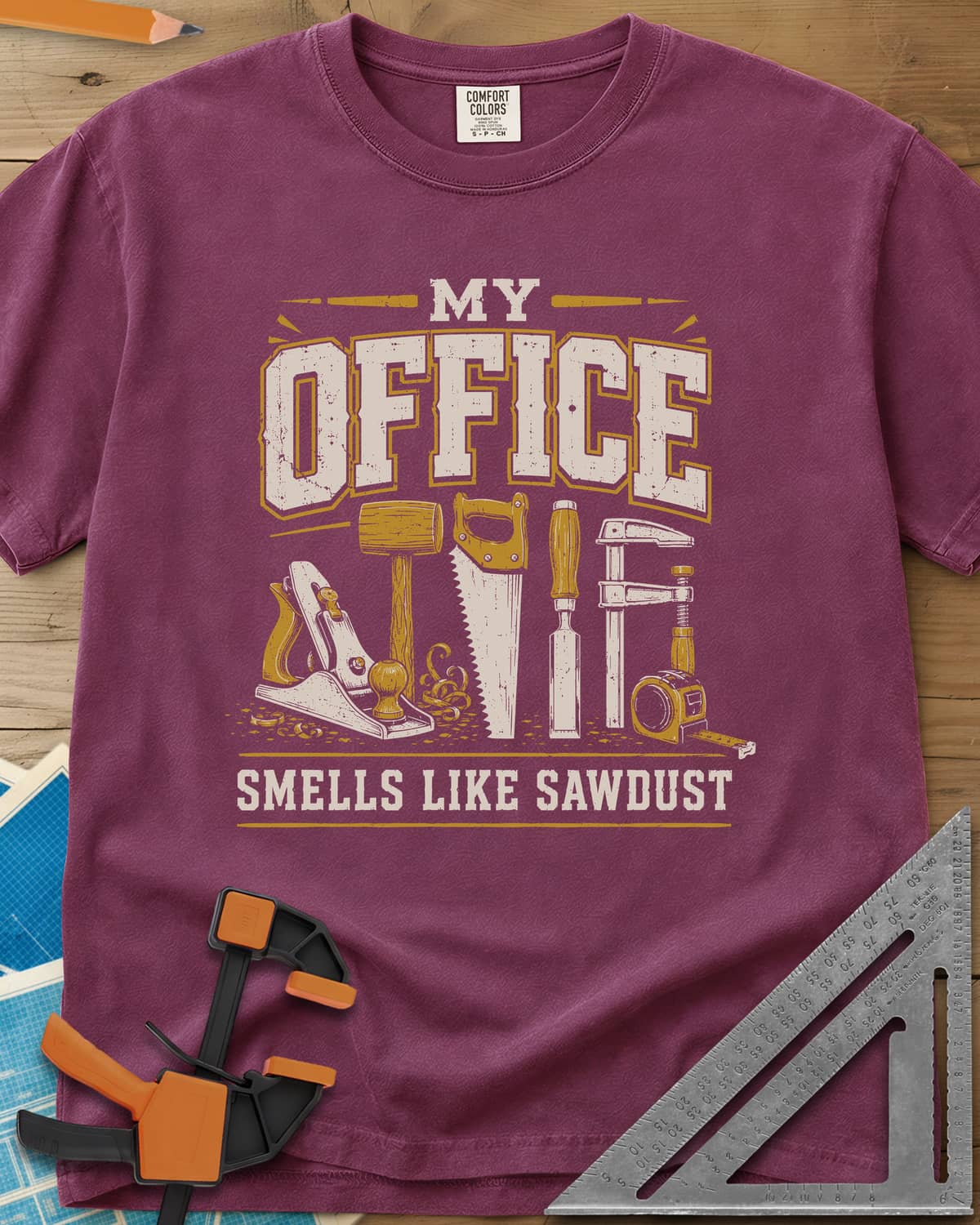My Office Smells Like Sawdust heavyweight tee in Berry, a row of hand tools: plane, mallet, saw, chisel, clamp, tape