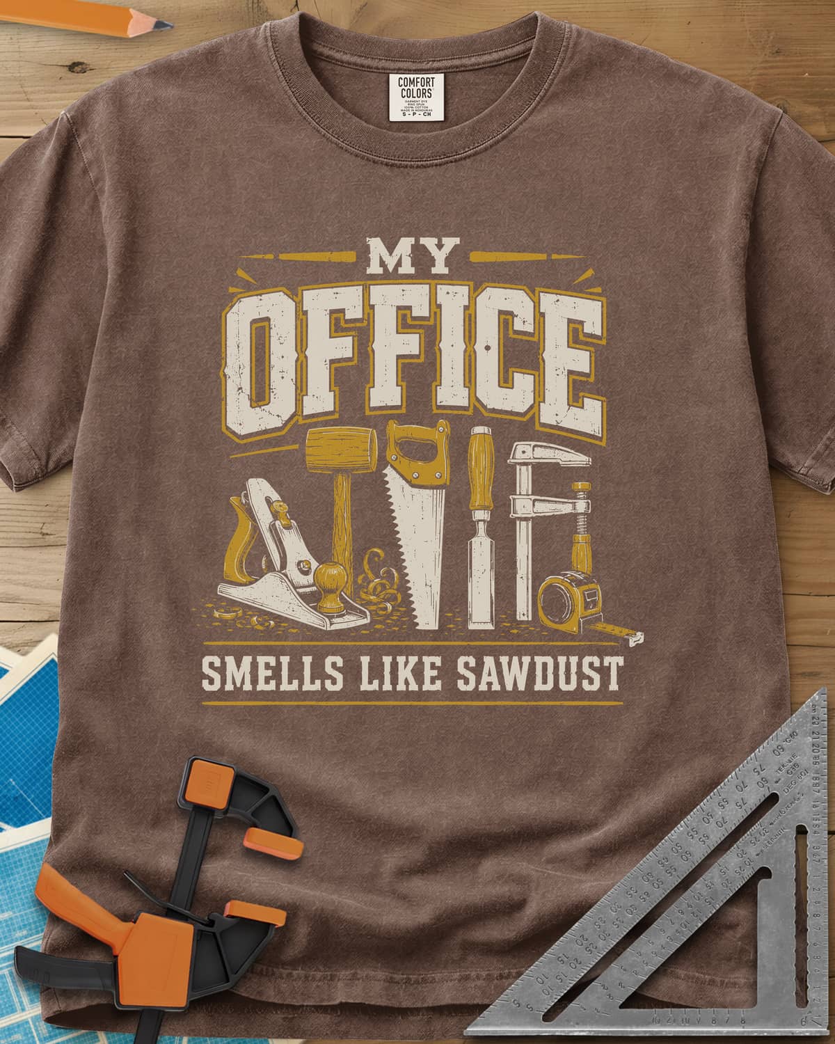 My Office Smells Like Sawdust heavyweight tee in Espresso, a row of hand tools: plane, mallet, saw, chisel, clamp, tape