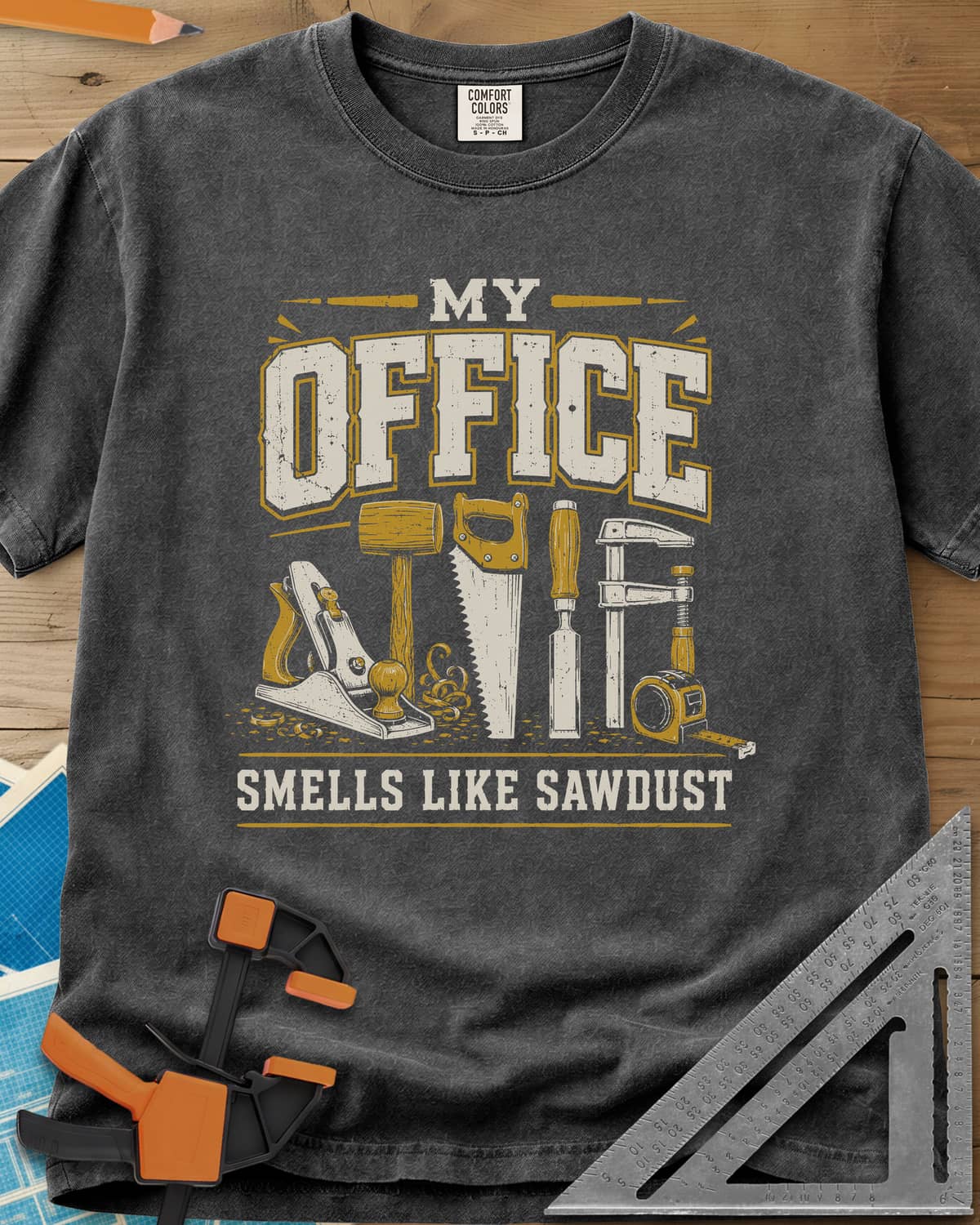 My Office Smells Like Sawdust heavyweight tee in Pepper, a row of hand tools: plane, mallet, saw, chisel, clamp, tape