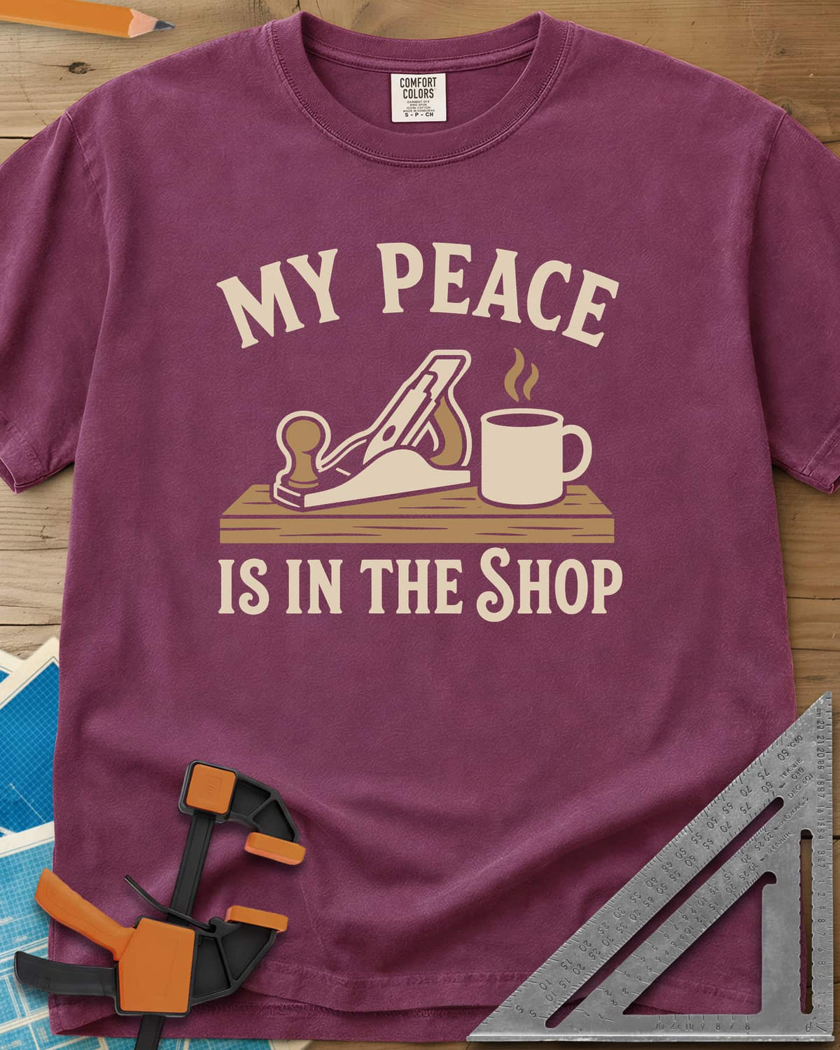 My Peace Is In The Shop heavyweight tee in Berry, a hand plane on a plank beside a steaming coffee mug