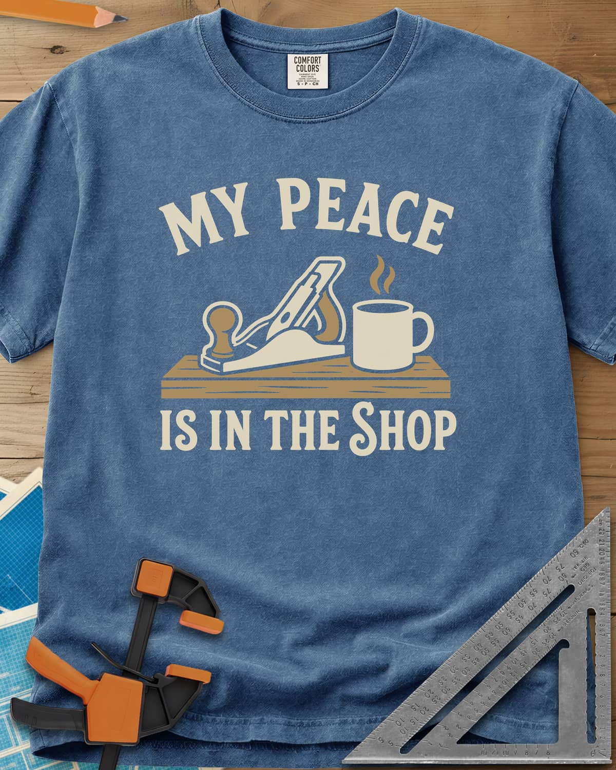 My Peace Is In The Shop heavyweight tee in Blue Jean, a hand plane on a plank beside a steaming coffee mug
