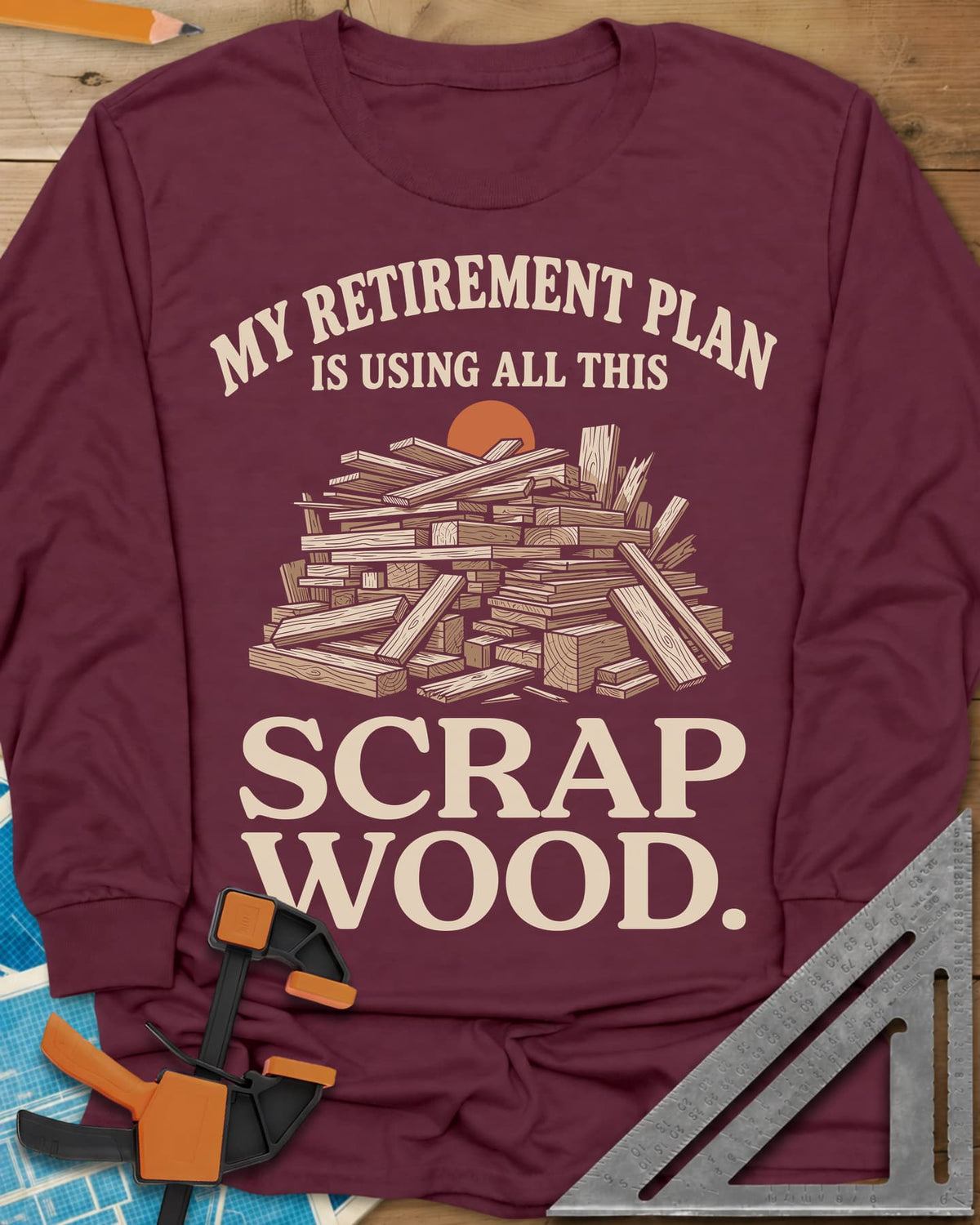 My Retirement Plan Scrap Wood long sleeve shirt in Maroon, a heaped pile of scrap boards in front of a setting sun