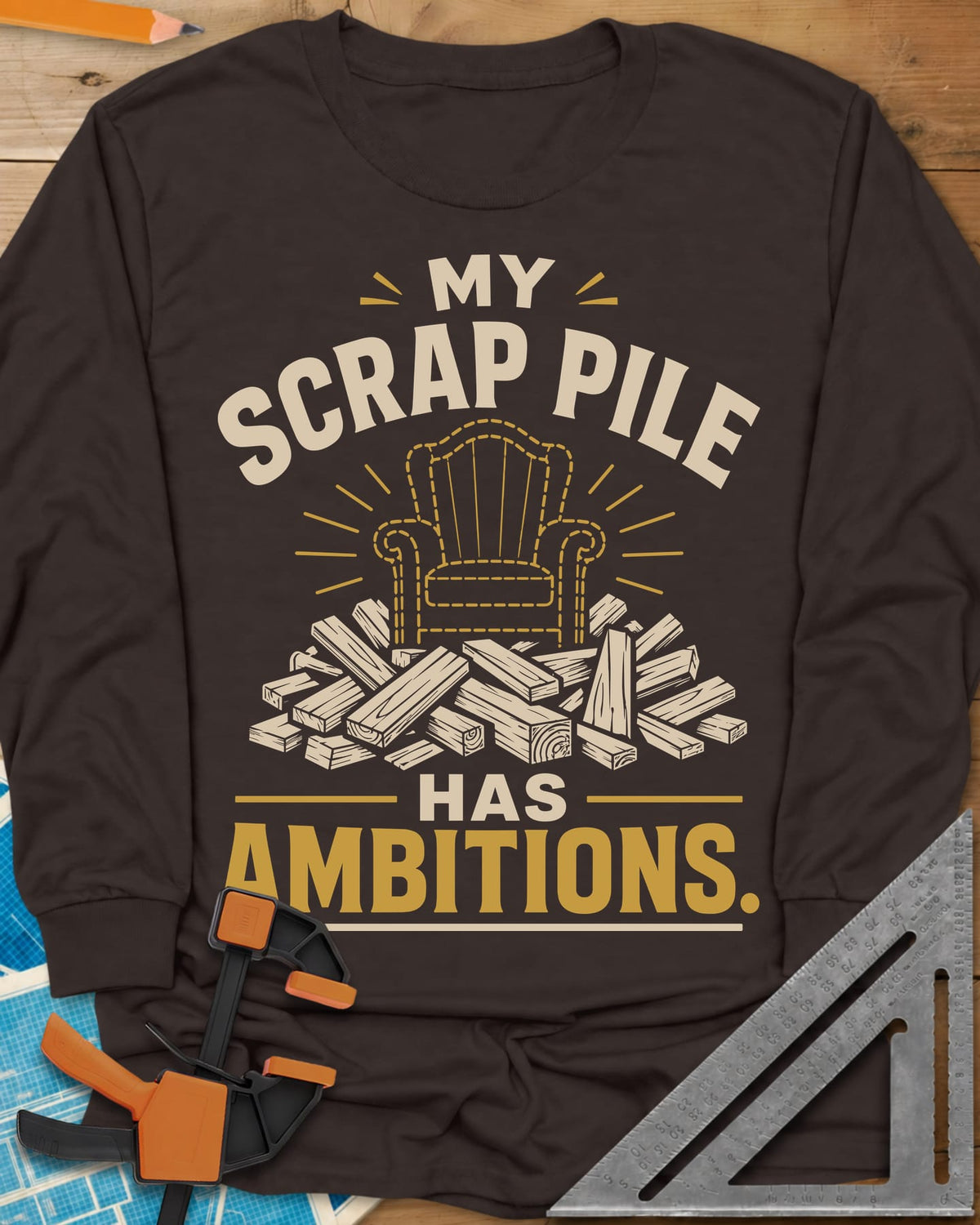 My Scrap Pile Has Ambitions long sleeve shirt in Dark Chocolate, a dotted gold armchair outline rising from a pile of wood