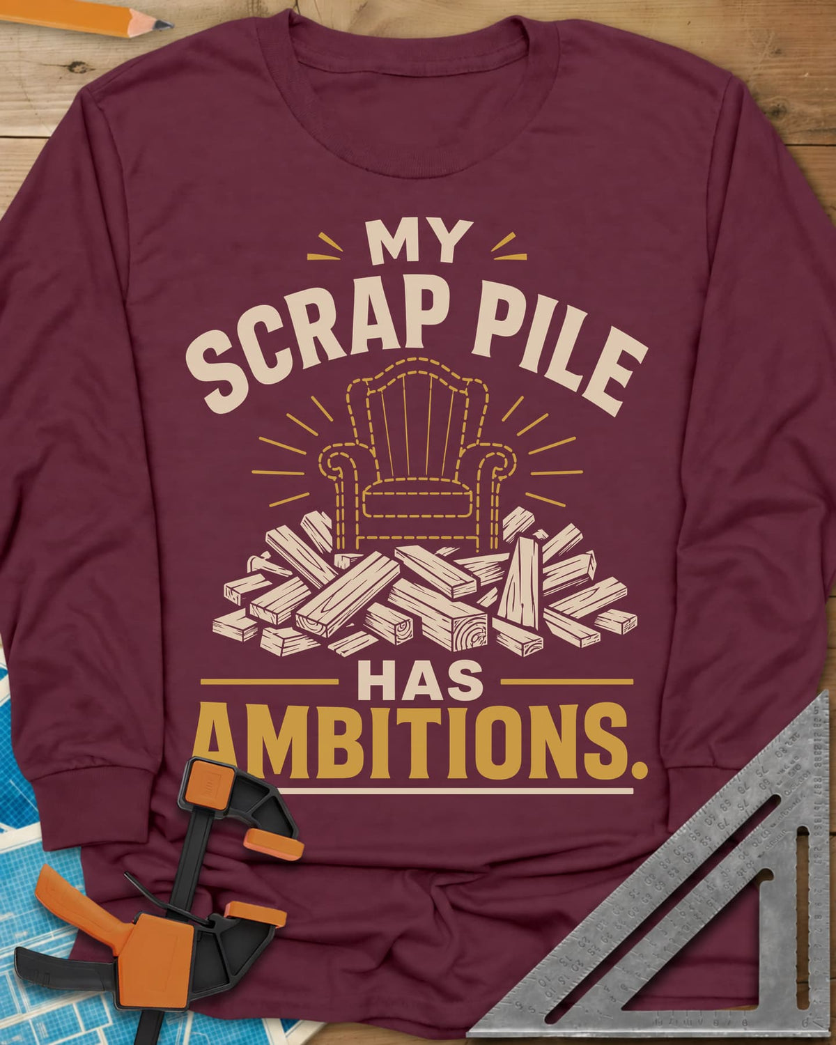 My Scrap Pile Has Ambitions long sleeve shirt in Maroon, a dotted gold armchair outline rising from a pile of wood offcuts