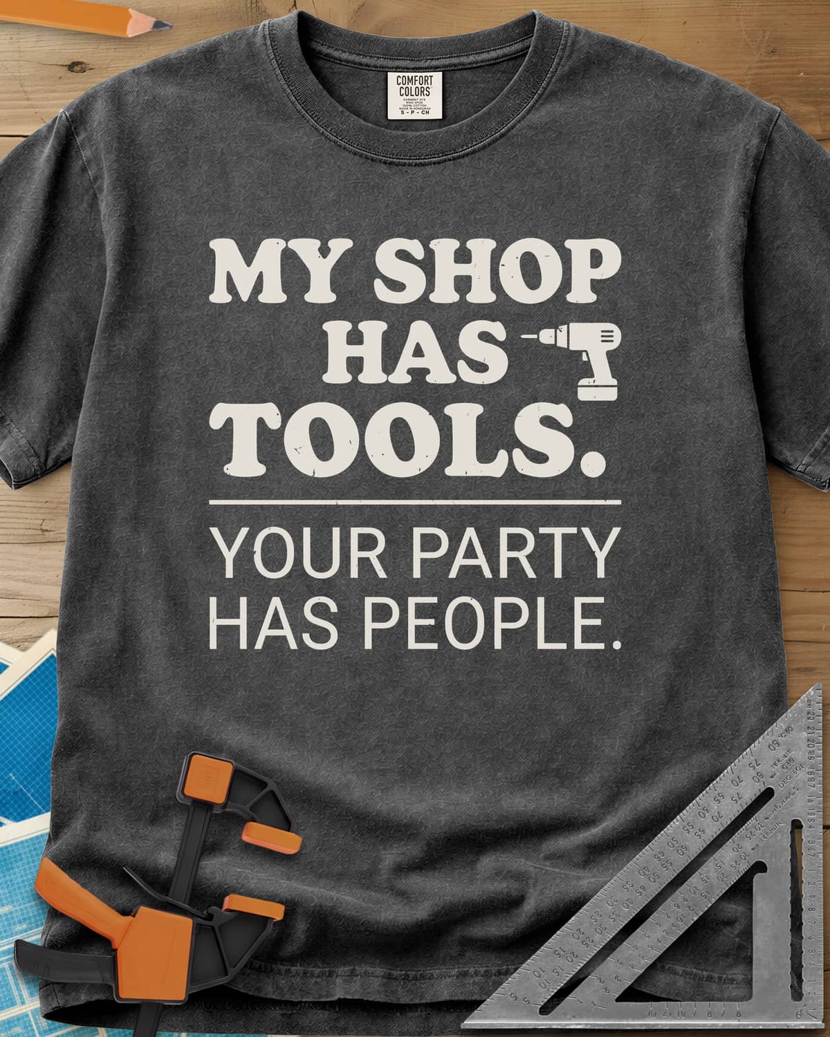 My Shop Has Tools Your Party Has People heavyweight tee in Pepper, two-part slogan split by a line, with a small cordless