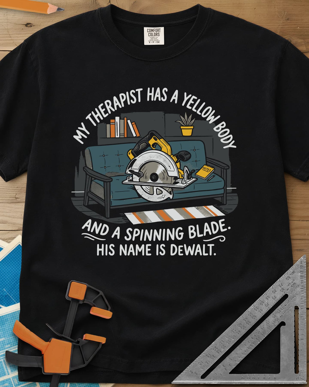 My Therapist Has A Spinning Blade heavyweight tee in Black, a cartoon yellow circular saw lounging on a teal couch